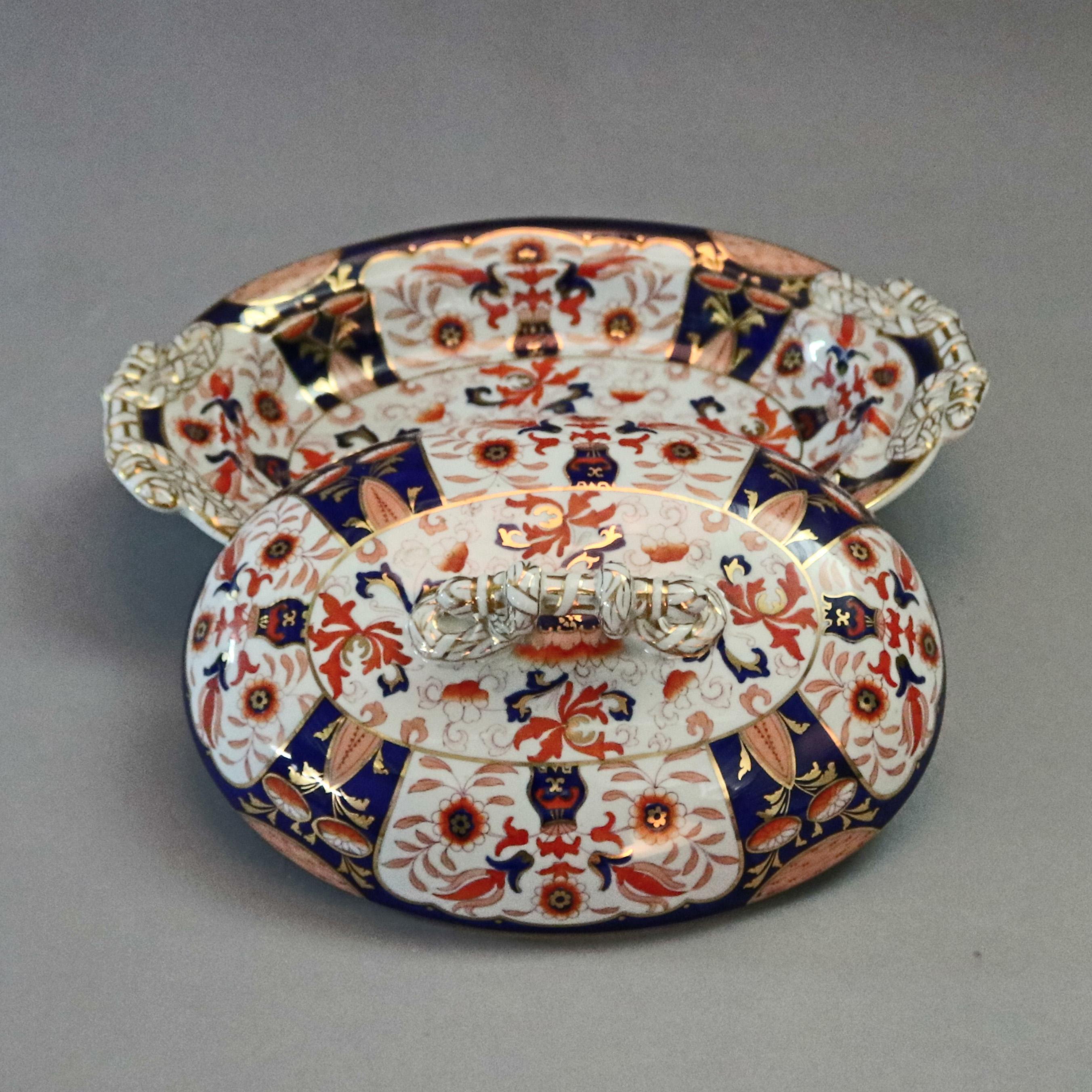 An antique Imari style chinoiserie Ashworth Ironstone lidded tureen offers all-over hand painted floral and foliate paneled decoration with gilt highlights, lid with gilt decorated stick form handle, maker's crown stamp on base as photographed,