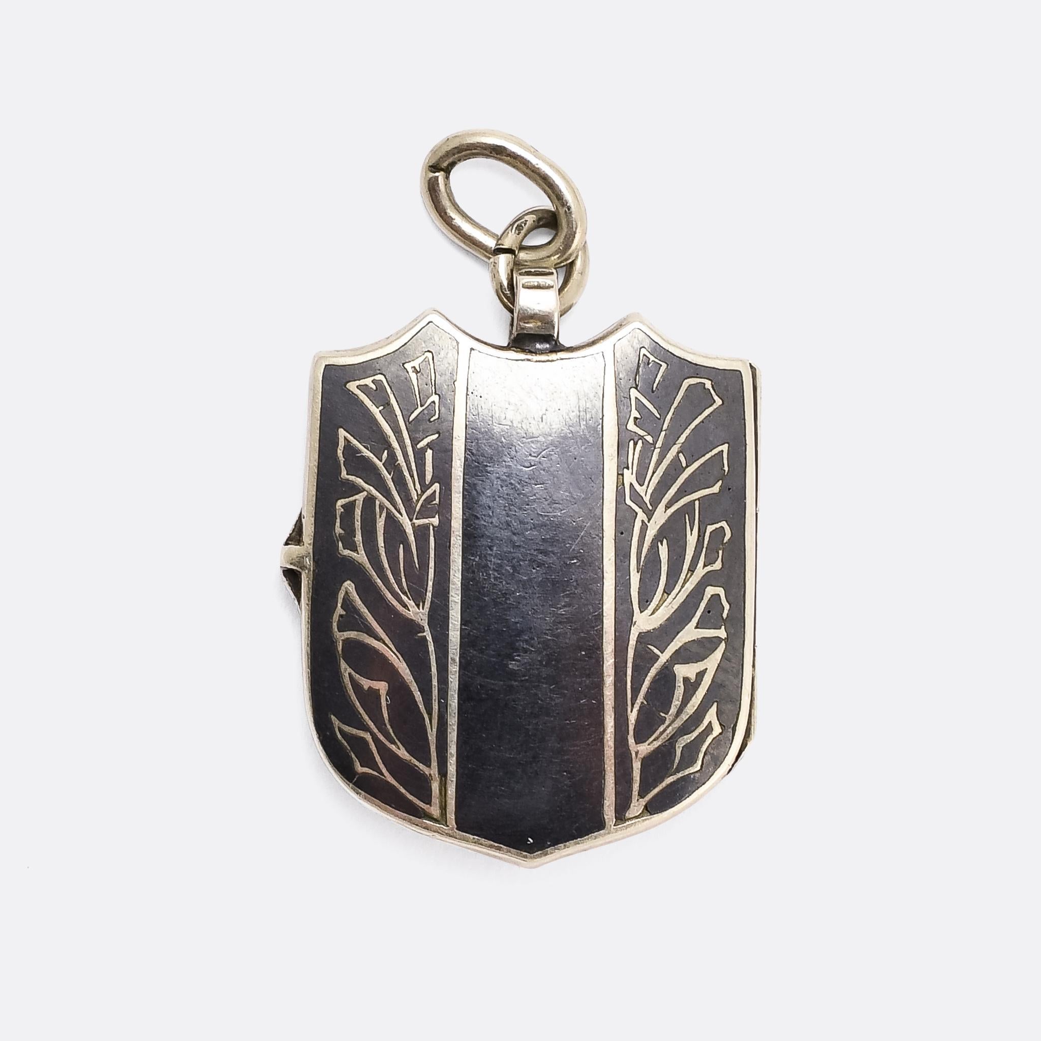 An attractive antique shield locket fashioned in niello silver. It's Russian, dating from the turn of the 20th century, with three gold stars down the middle and stylized thistles (?) on either side. It opens to reveal two oval shaped compartments