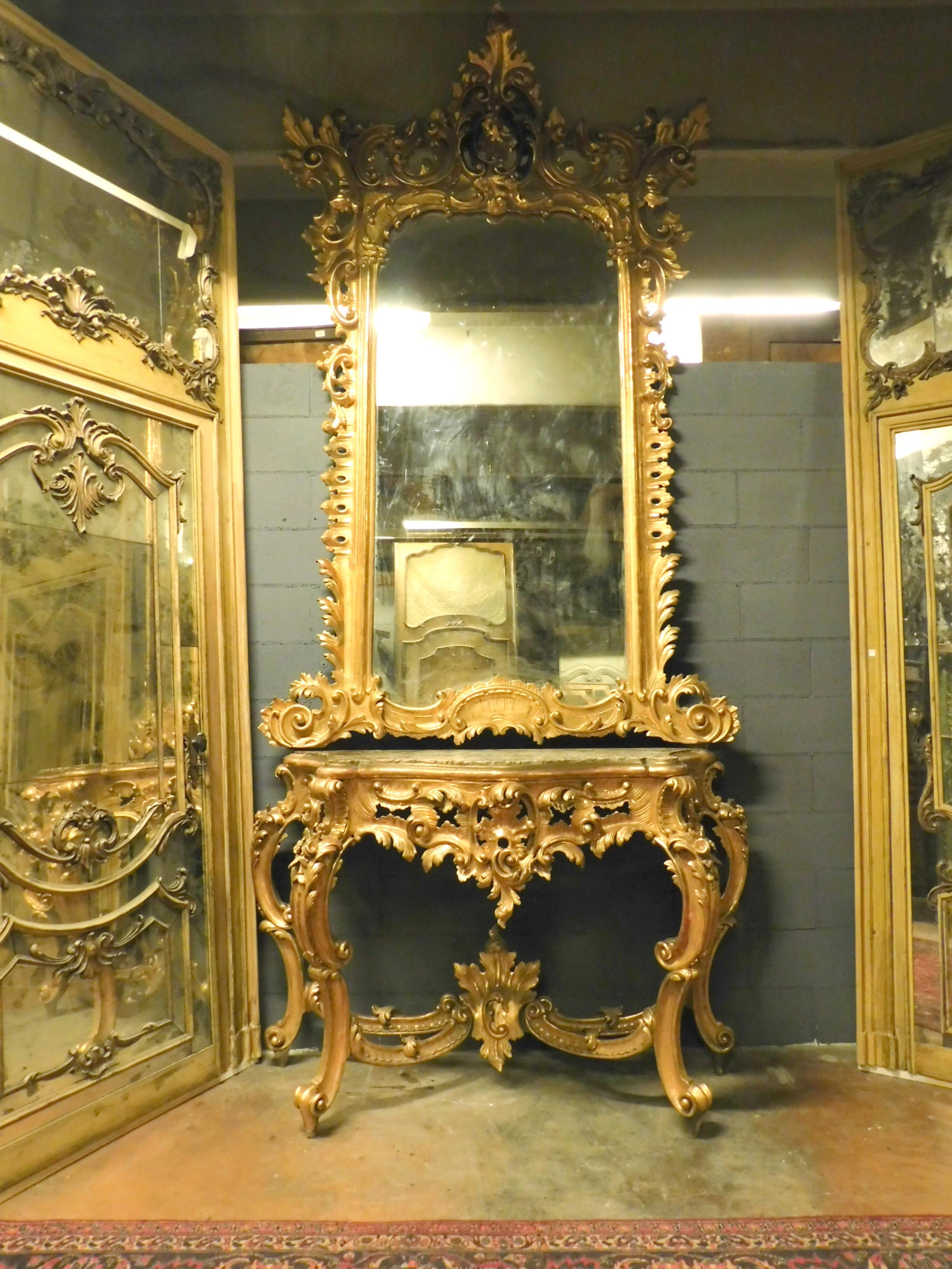 Ancienne et importante console dorée, composée d'un miroir en bois doré, avec de très riches sculptures, et d'un plateau de console en marbre avec des pieds sculptés et dorés. Provenant d'un important bâtiment historique de Naples (Italie),