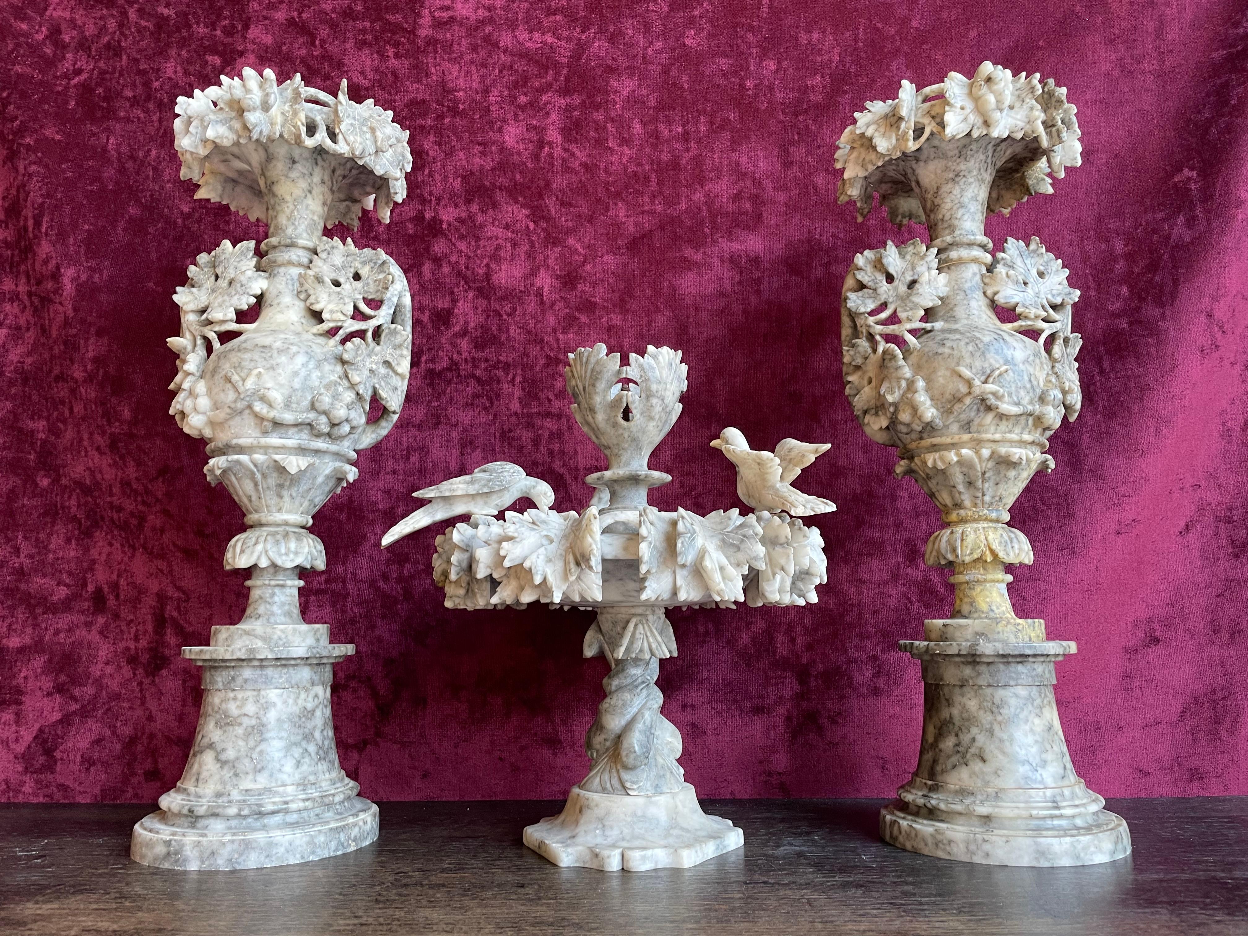 Early 1900s pair of alabaster vases with an alabaster 'fountain' with birds in the middle.

Have you ever tried to hand carve a figure out of a piece of natural mineral stone? Only than you can really come close to having an idea of how remarkable