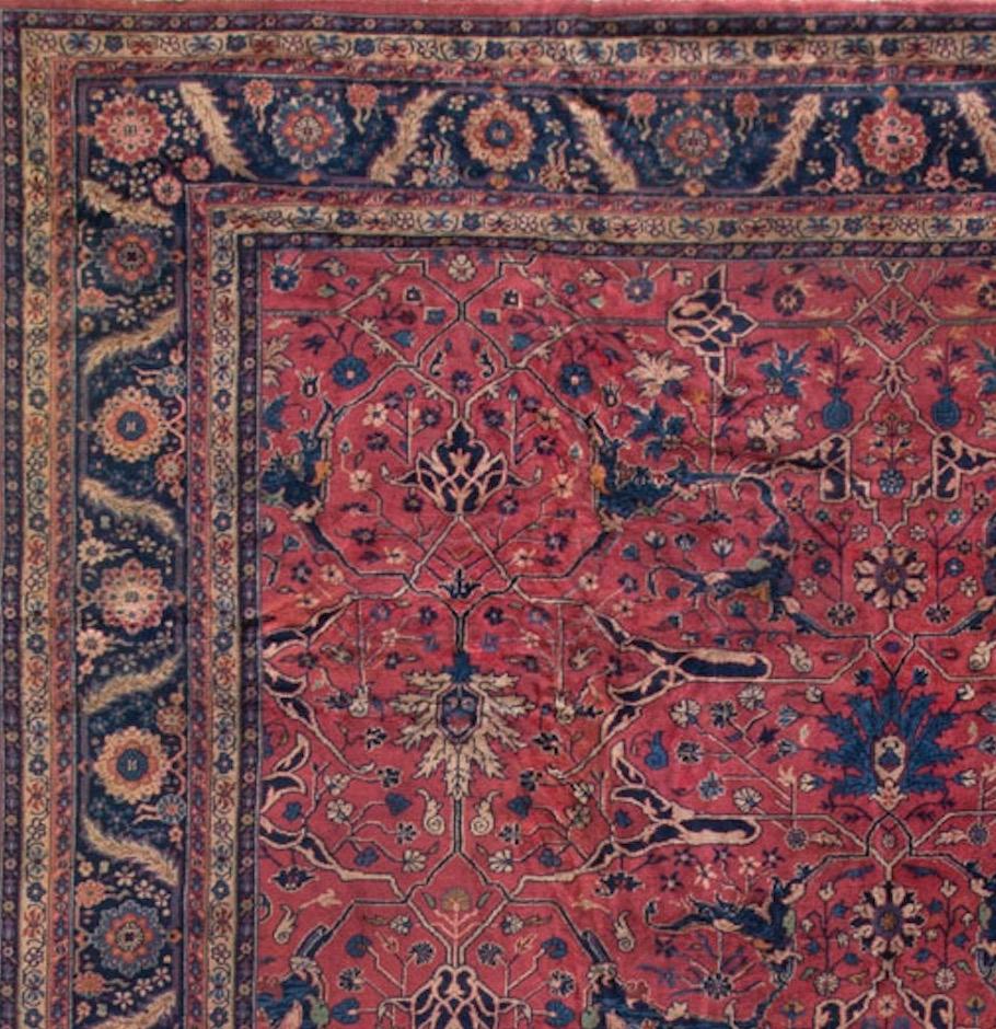 This squarish antique Agra rug has a central deep red field with a distinctive floral and trellis designs. The main border enclosed by six minor guard borders is in navy and repeats the central design theme. Measures: 13'0 x 14'5