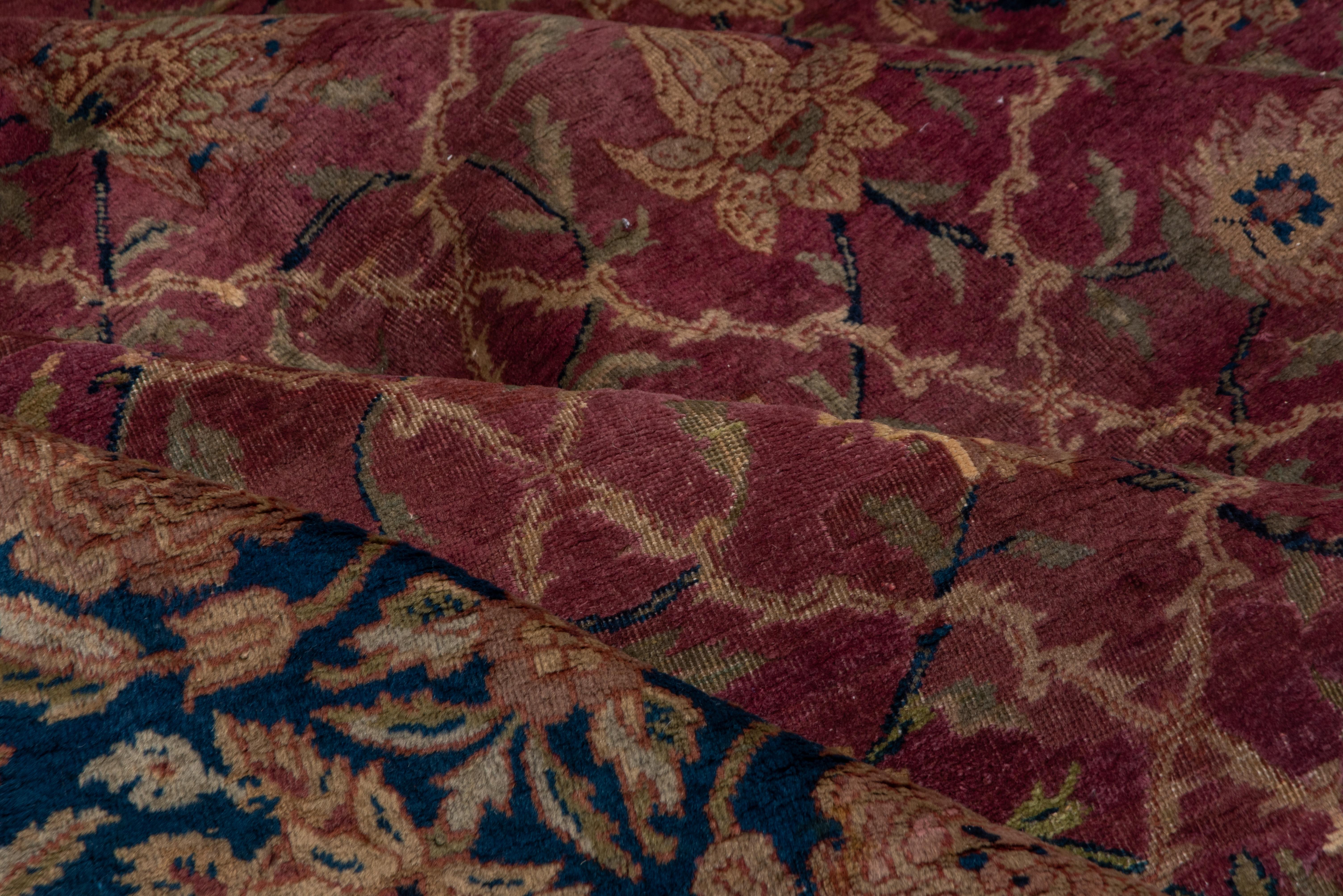 Ce tapis de ville du nord de l'Inde suit de près le modèle et la palette des tapis de pashmina du Cachemire du XVIIe siècle, avec un fond bordeaux prune proprement divisé par un treillis moghol ivoire renfermant des rosettes. Bordure principale à