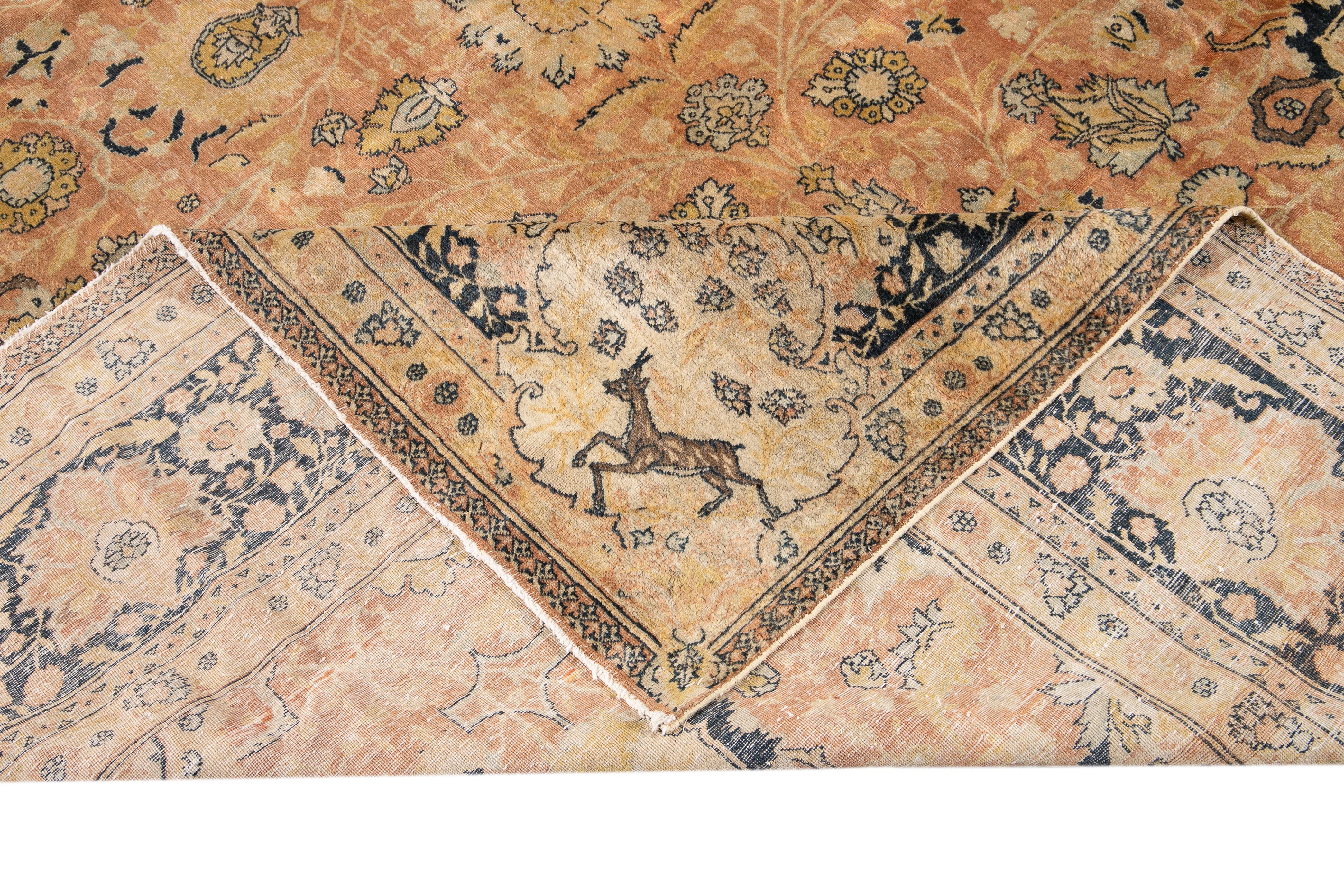 Schöner antiker, handgeknüpfter Agra-Wollteppich mit einem floralen Medaillonmuster auf einem pfirsichfarbenen Feld. Dieser indische Teppich hat Akzente in Braun, Blau und Gelb.

Dieser Teppich misst: 11'8
