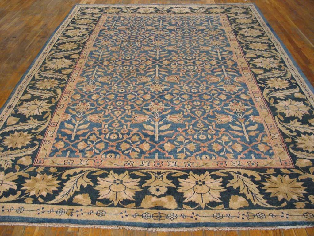 A medium-light blue ground is elegantly patterned by a Mughal-style diamond lattice enclosing both complete flowers and smaller, similar diamonds. The pattern evenly reflects across the center line. This antique Indian town carpet shows a navy