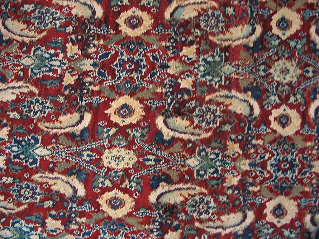 The rich red field of this small square antique northern Indian carpet features a dense all-over Herati pattern with particularly prominent barbed ‘fish’ leaves in sandy cream. The reversing turtle border abrashs between light blue and royal blue.
