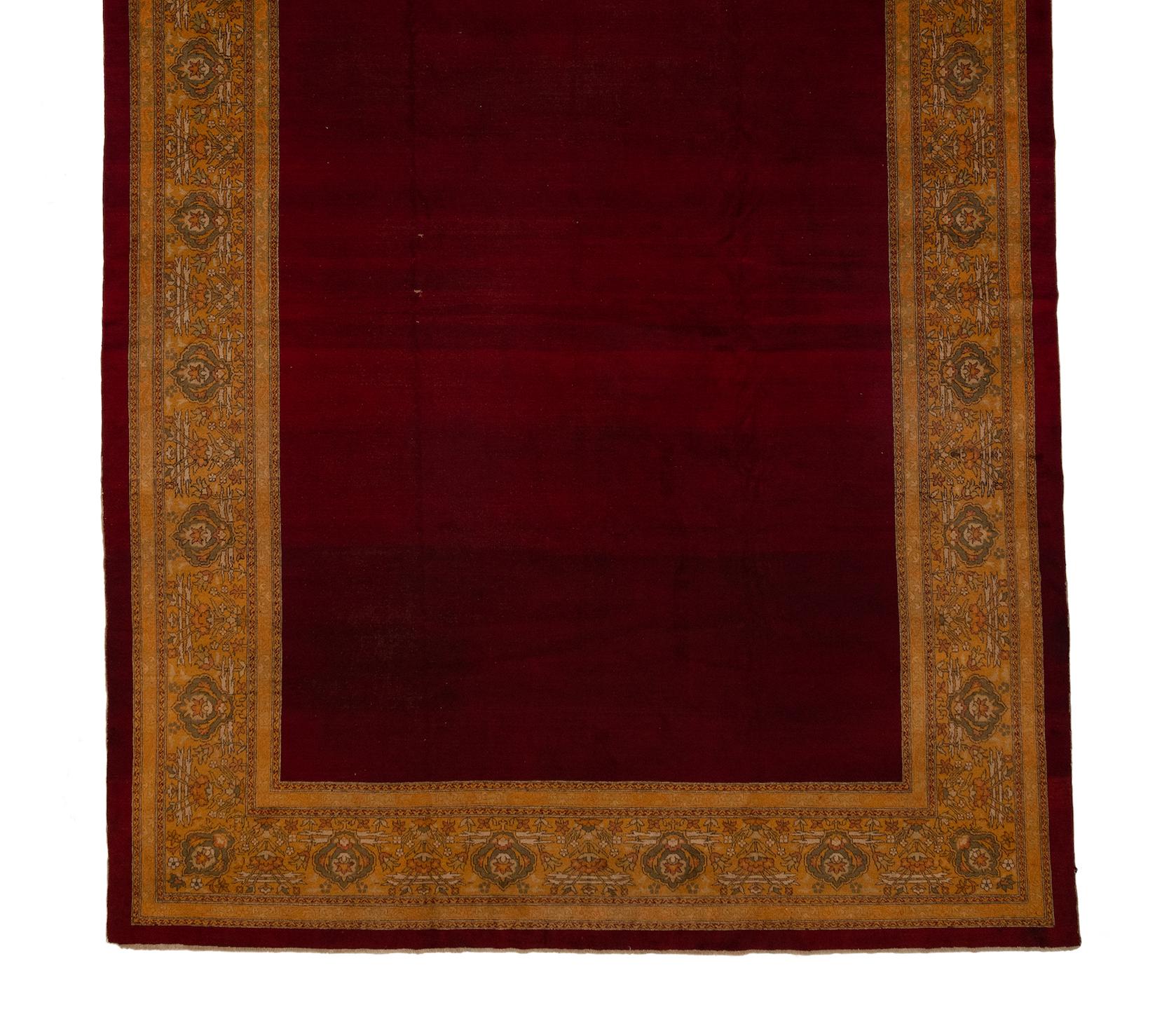 Si tratta di un antico tappeto indiano Agra, risalente al 1880 circa. Questo tappeto è definito dall'uso squisito del colore. Ha un bellissimo campo aperto rosso zaffiro e un bordo giallo zafferano con disegni floreali in verde oliva, marrone e