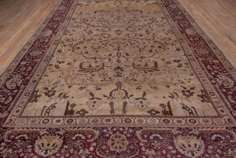 This northern Indian city carpet shows long, bi-tonal leaves looping over one another while palmettes and flowers are displayed on the buff field. Red-brown, dark umber and ecru highlight the pattern while the dark brown border shows assorted