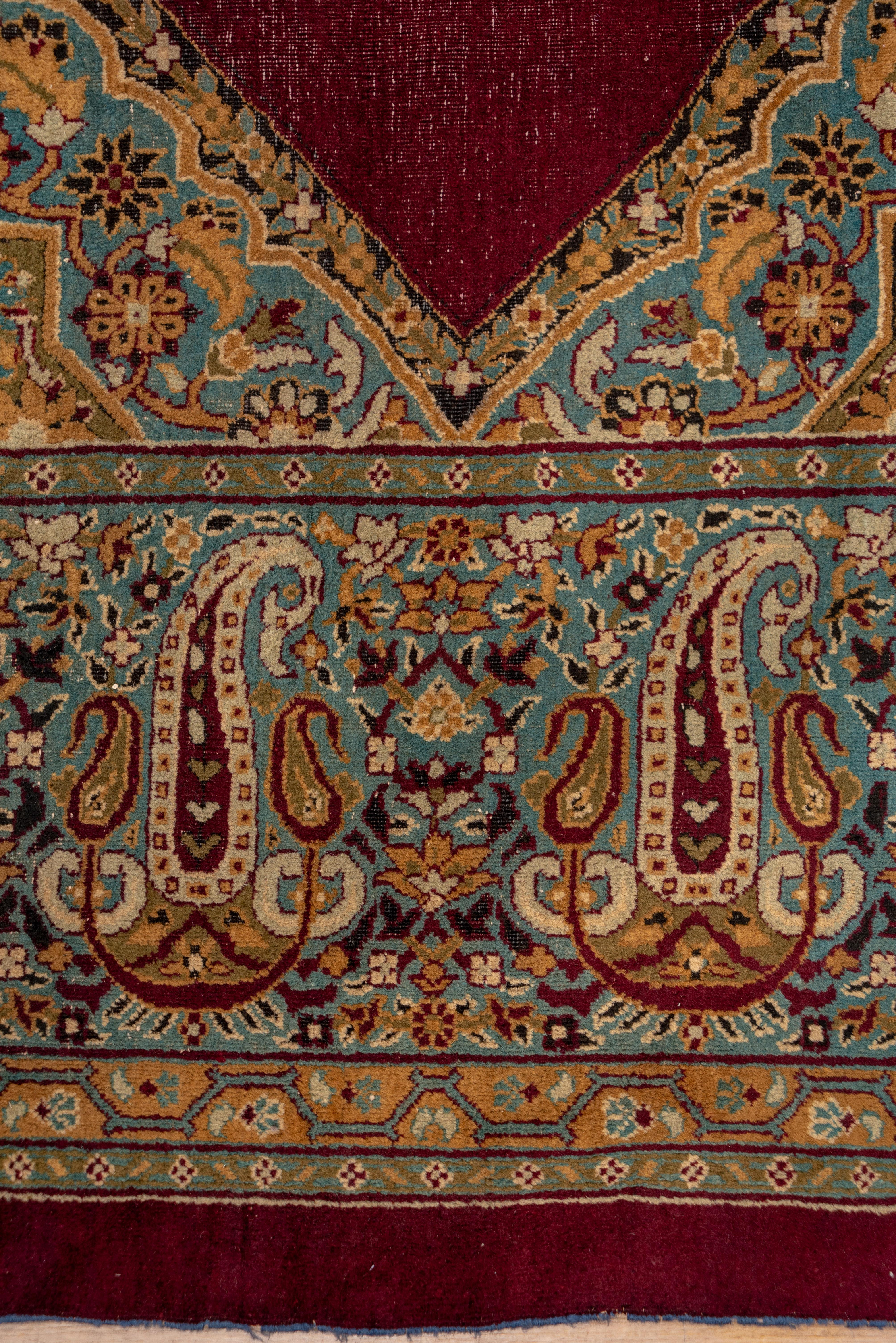 A very striking northern Indian urban carpet with a plain zig-zag burgundy field centered by a pole medallion of three red, rosette-filled conjoint diamonds with pale blue pattern en suite triangular side fillers. Ice blue border of large and small