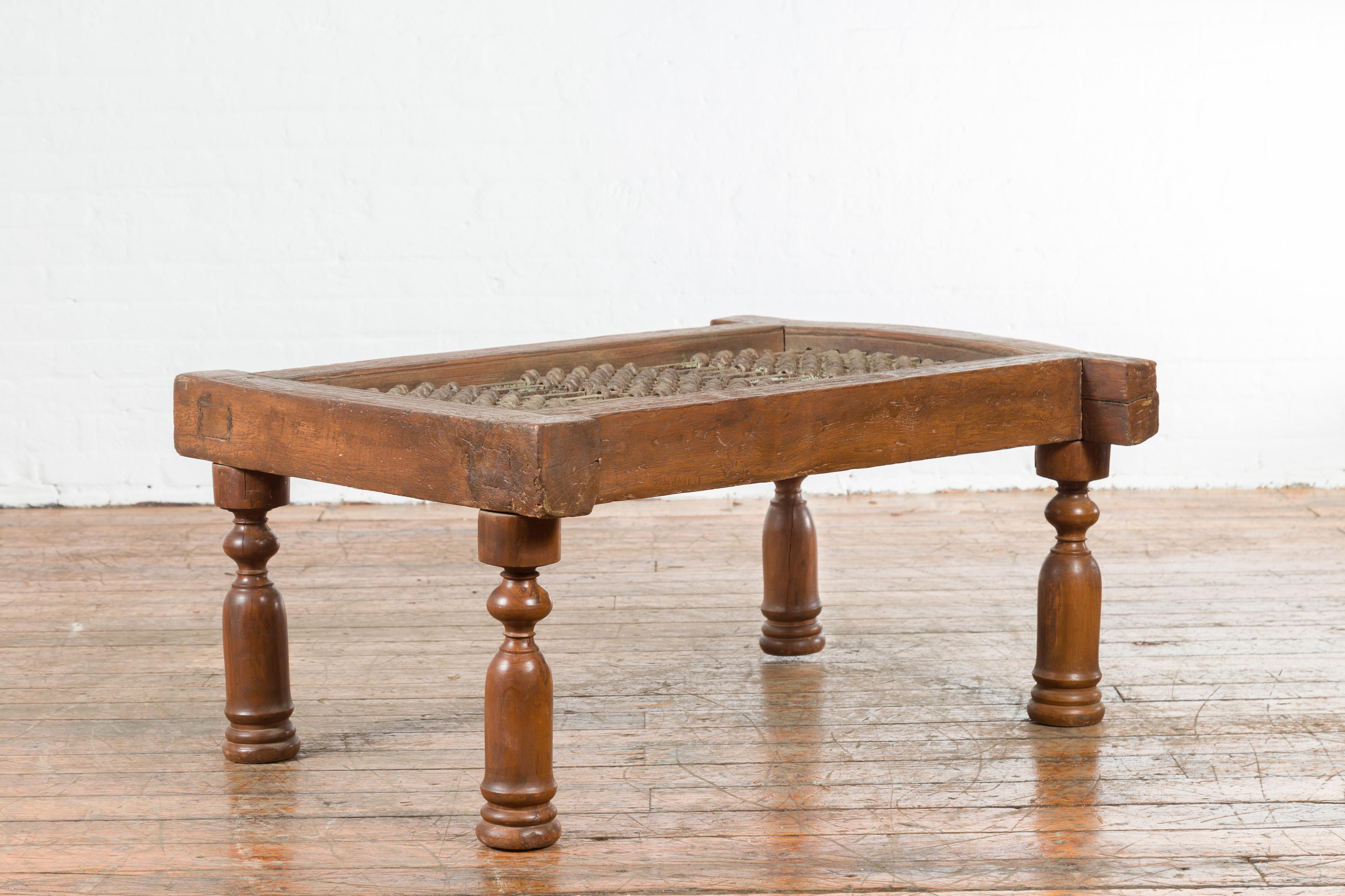 An antique Indian window grate with arching motifs from the early 20th century, made into a coffee table. Created in India during the early years of the 20th century, this Indian window grate is resting on four turned baluster-type legs. Perfectly