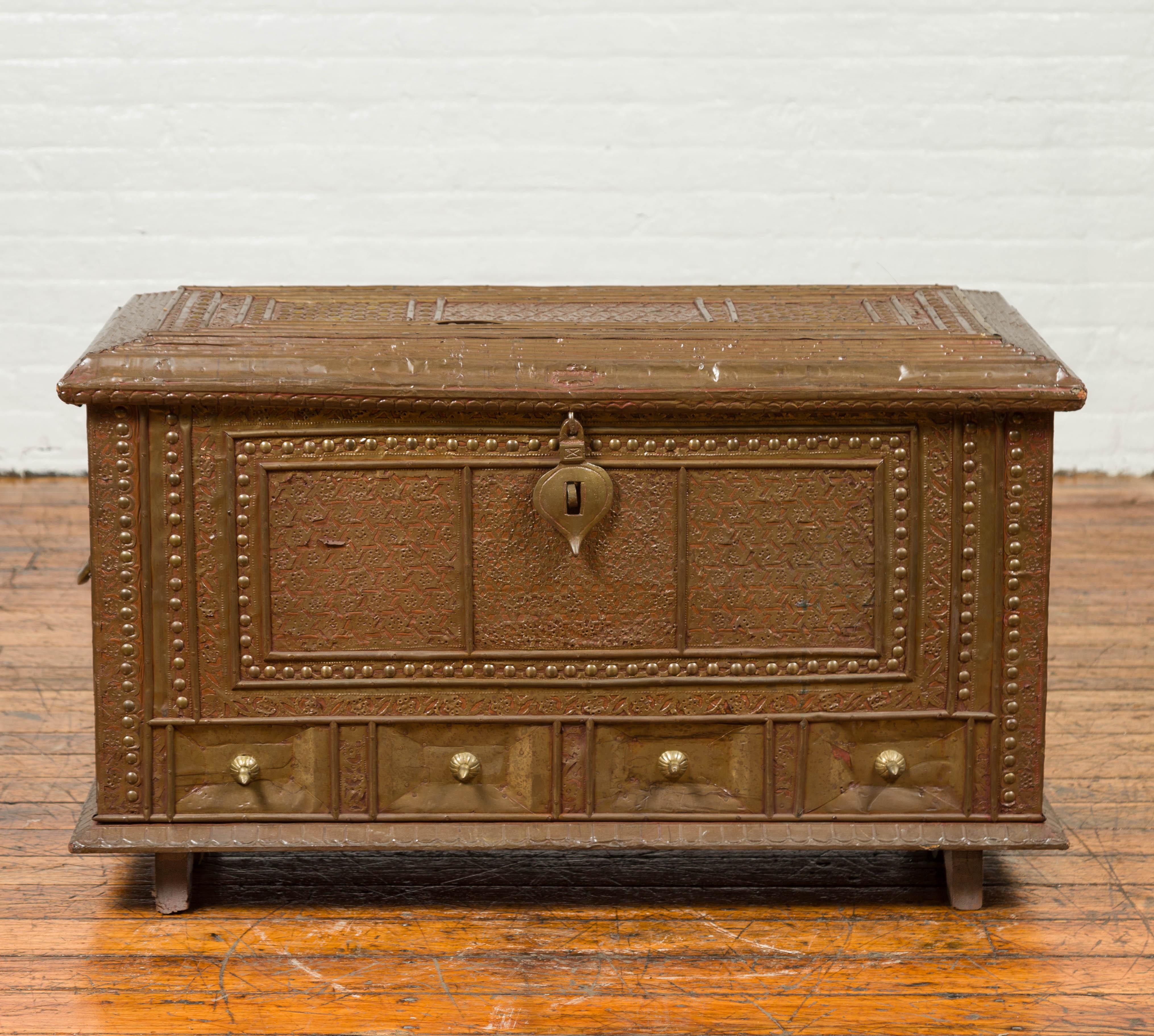 An antique Indian blanket chest with bronze sheathing, geometric patterns and studs. This Indian blanket chest features a rectangular top with raised effect, opening up thanks to a teardrop latch to reveal a large space, convenient to store blankets