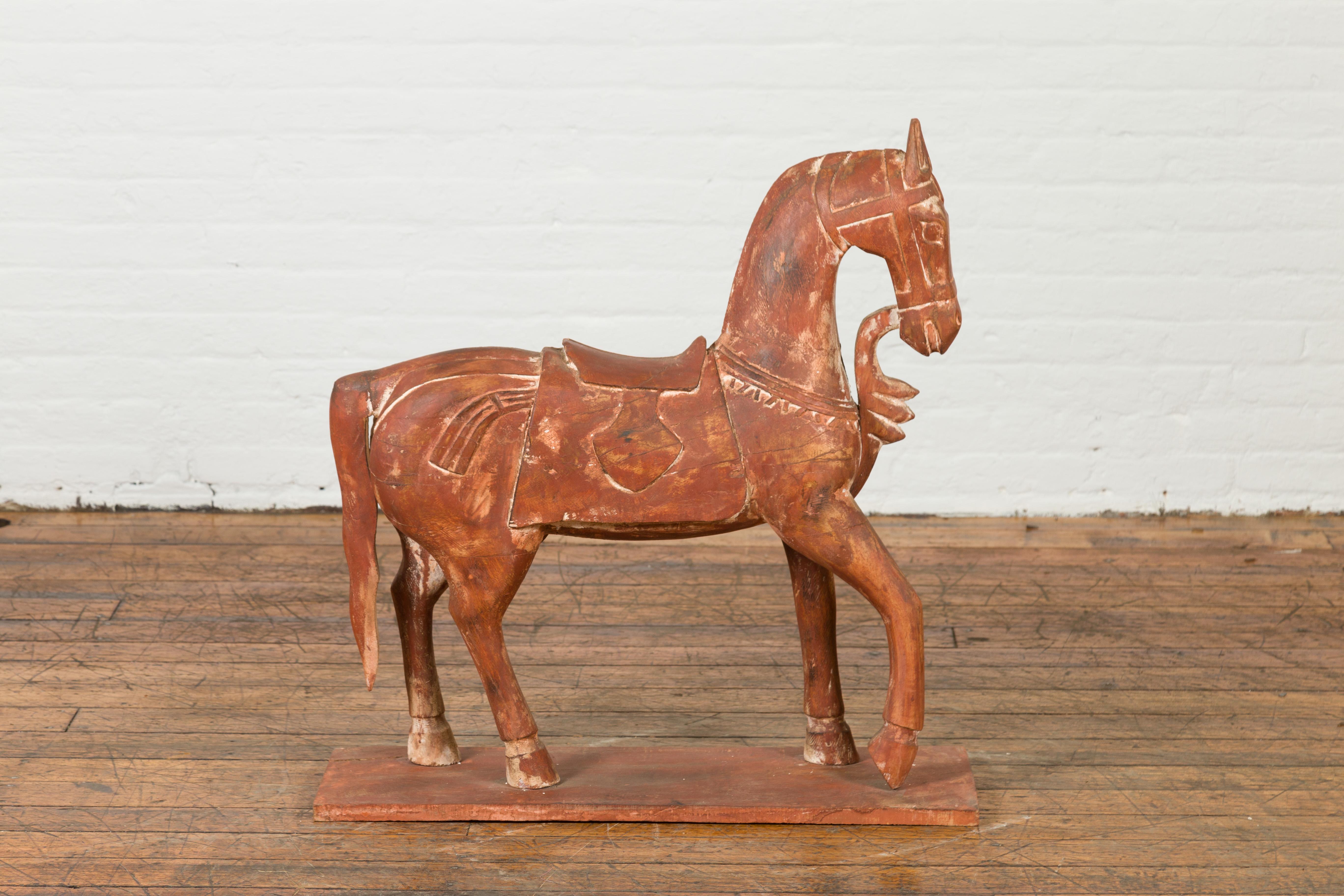 An antique Indian carved wooden Mogul horse from the 20th century, with weathered patina. Carved in India during the 20th century, this Mogul wooden horse charms us with its archaic features and distressed appearance. Standing on his four legs, the