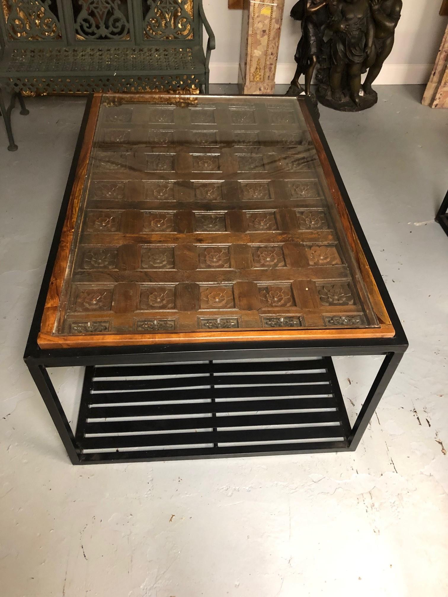 Late 1800s antique carved wood door or ceiling panel made into a coffee or accent table with a glass top. The panel was put into a new custom made metal base which looks fantastic together. This table is from Rajasthan India which is one of India's