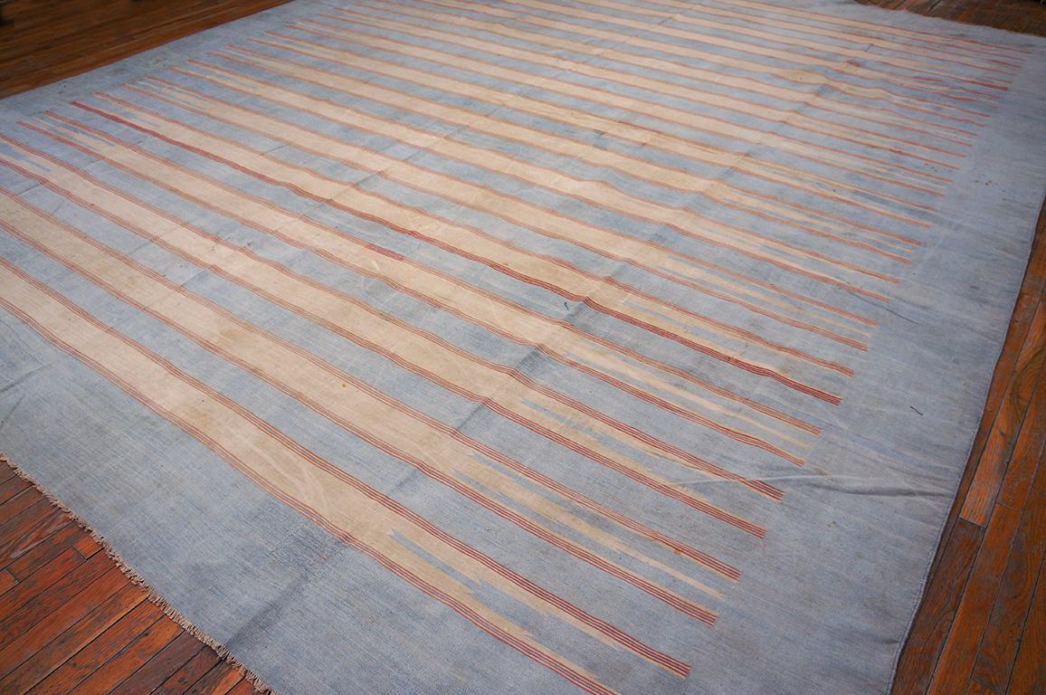 Dhurries are the ultimate summer vacation house floor coverings. 
This all cotton, good condition semi-square flat-weave shows a narrow horizontal line pattern stopping short of the edges in brown and pale yellow, on the ecru ground. Thin spearhead