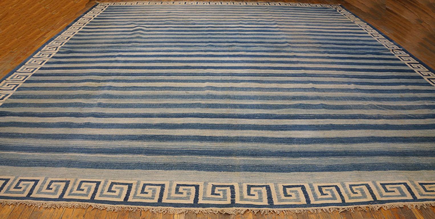 An ecru, light blue and darker denim blue define a small-scale squared wave border surrounding a light and darker blue horizontally striped field with dark blue hairline dividers. Visible abrash in the blues. Good condition for this antique