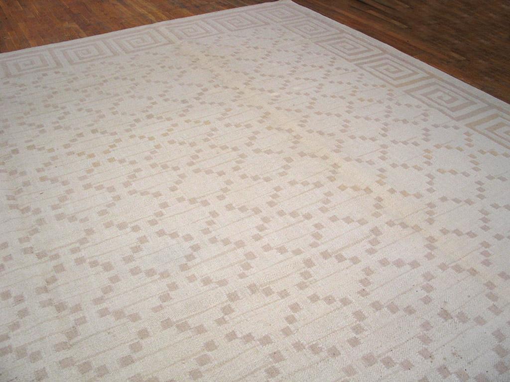 Ziemlich modern, aber im klassischen Dhurrie-Stil mit einer dramatischen quadratischen Wellenbordüre und einem offenen Rautengitter aus winzigen Quadraten, alles in cremefarbenem Beige und Hellbraun. Sieht ein wenig modern aus. Die Umrandung ist auf