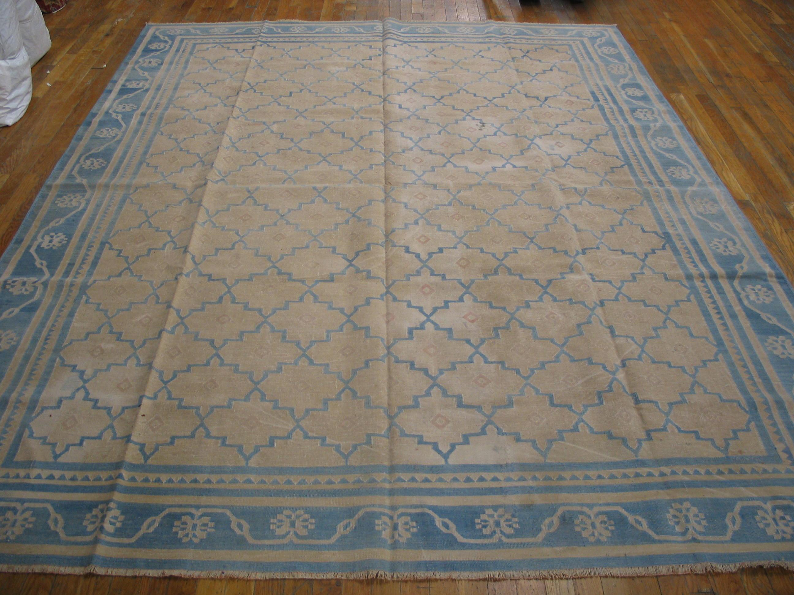 The sandy-straw field is organized precisely by a stepped blue lozenge lattice enclosing a small lozenge on each reserve. Denim blue palmette and meander main border and several inner stripes, plain and decorated. Antique all-cotton tapestry woven