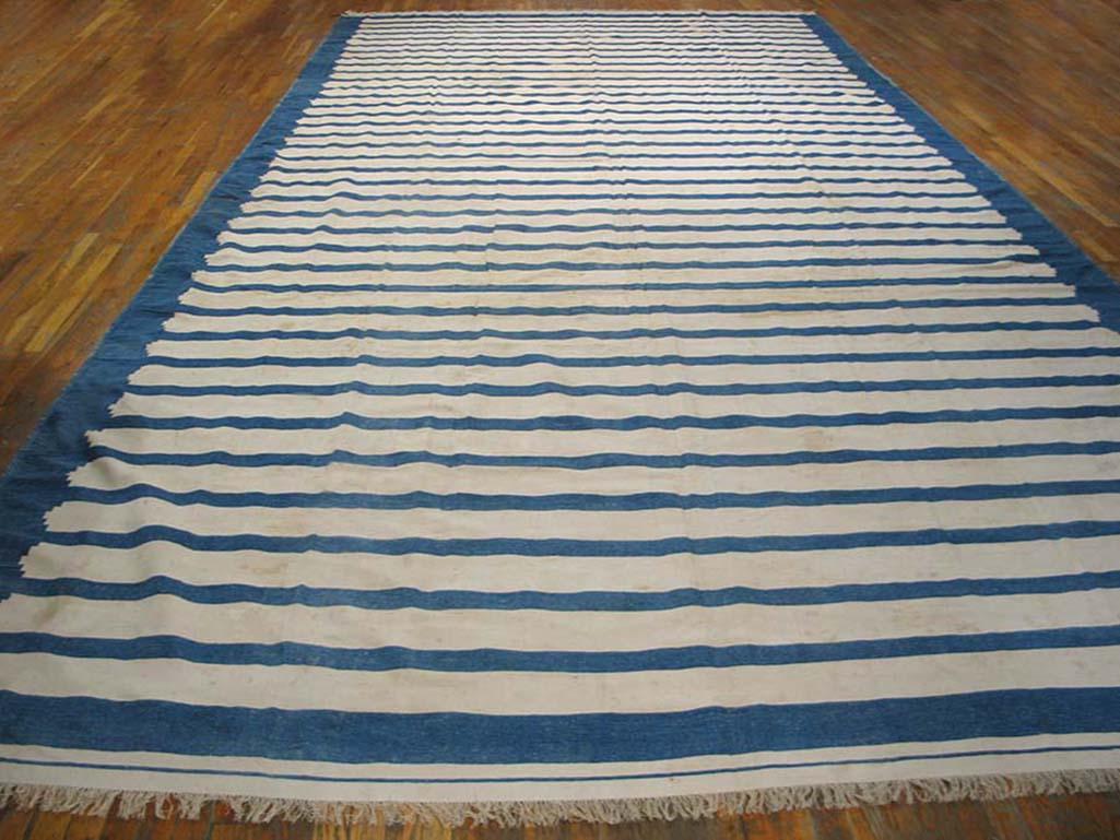 Although denim blue grounded, the off white broader stripes with their stepped ends chromatically predominate. At each end is a full-width ecru band. Gallery carpet format, good condition, almost antique all-cotton Indian flat-weave.