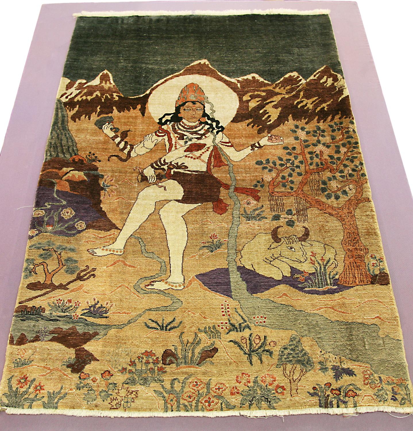 This is an antique silk Deccani rug woven in India during the beginning of the 20th century circa 1900 -1920's and measures 90x 63CM in size. This rug's design is of an Indian God set in nature with snowcapped mountains in the background. Also, in