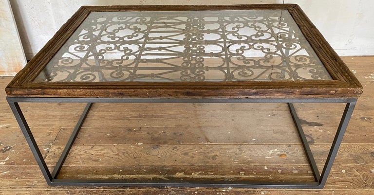 An antique 19th Century Indian wood and distressed metal window grate made into a coffee table.  The metal work of this particular window guard is especially intricate and beautifully designed.  The table is raised on a newly made iron base making
