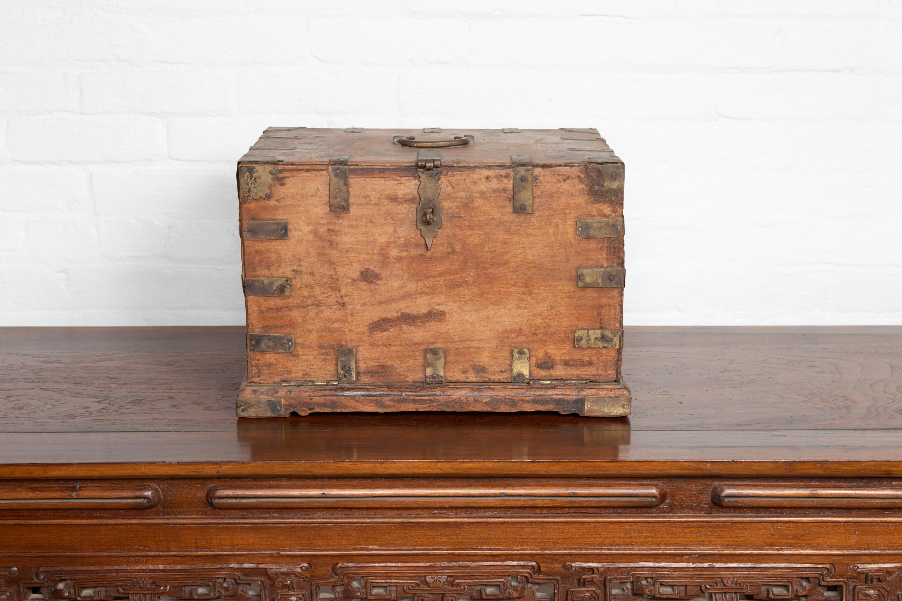 An antique Indian wooden jewelry box from the 19th century, with drop front and six hidden drawers. Born in India during the 19th century, this charming jewelry box features a nicely rustic appearance. Presenting a linear frame accented with brass