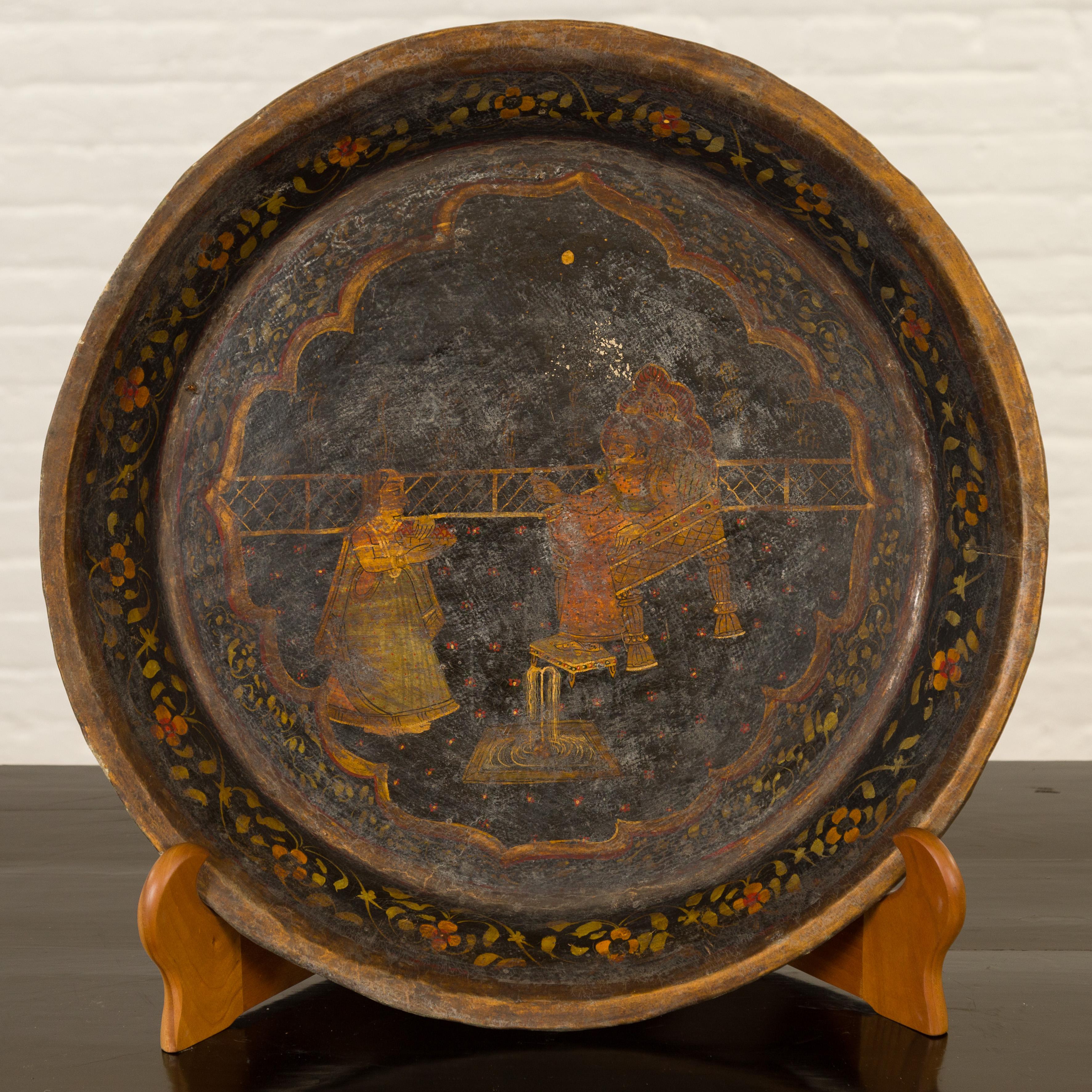 An antique Indian market tray from the 19th century, with Mughal inspired hand painted décor. Created in India, this market tray features a Mughal inspired hand painted décor. Two characters, depicted in three-quarter profile, boast delicate golden