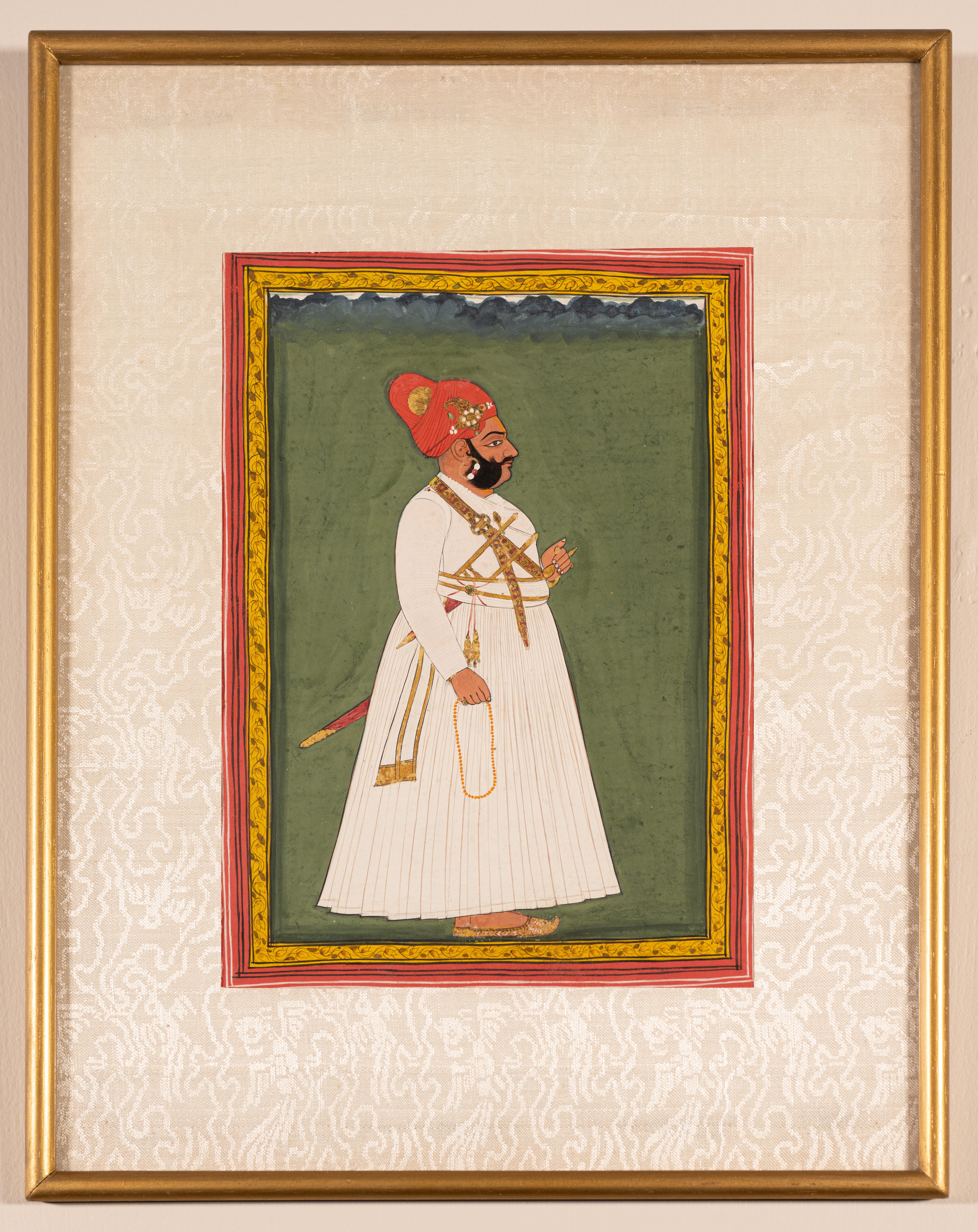 Offered here is an antique painting of an Indian Maharaja in gouache and gold on paper c. early 19th century or 1800.

A burly Maharaja stands in profile wearing a white jama or garment against an olive green background with a hint of the sky along
