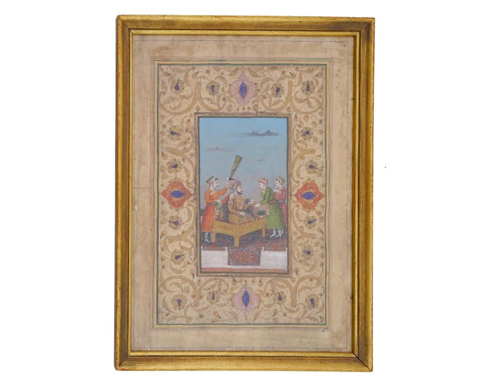 An antique Indian Mughal Empire miniature painting executed in gouache and embellished with gold on paper, portrays a captivating court scene wherein a ruler engages with nobles. These Mughal miniatures are esteemed for their intricate detail,