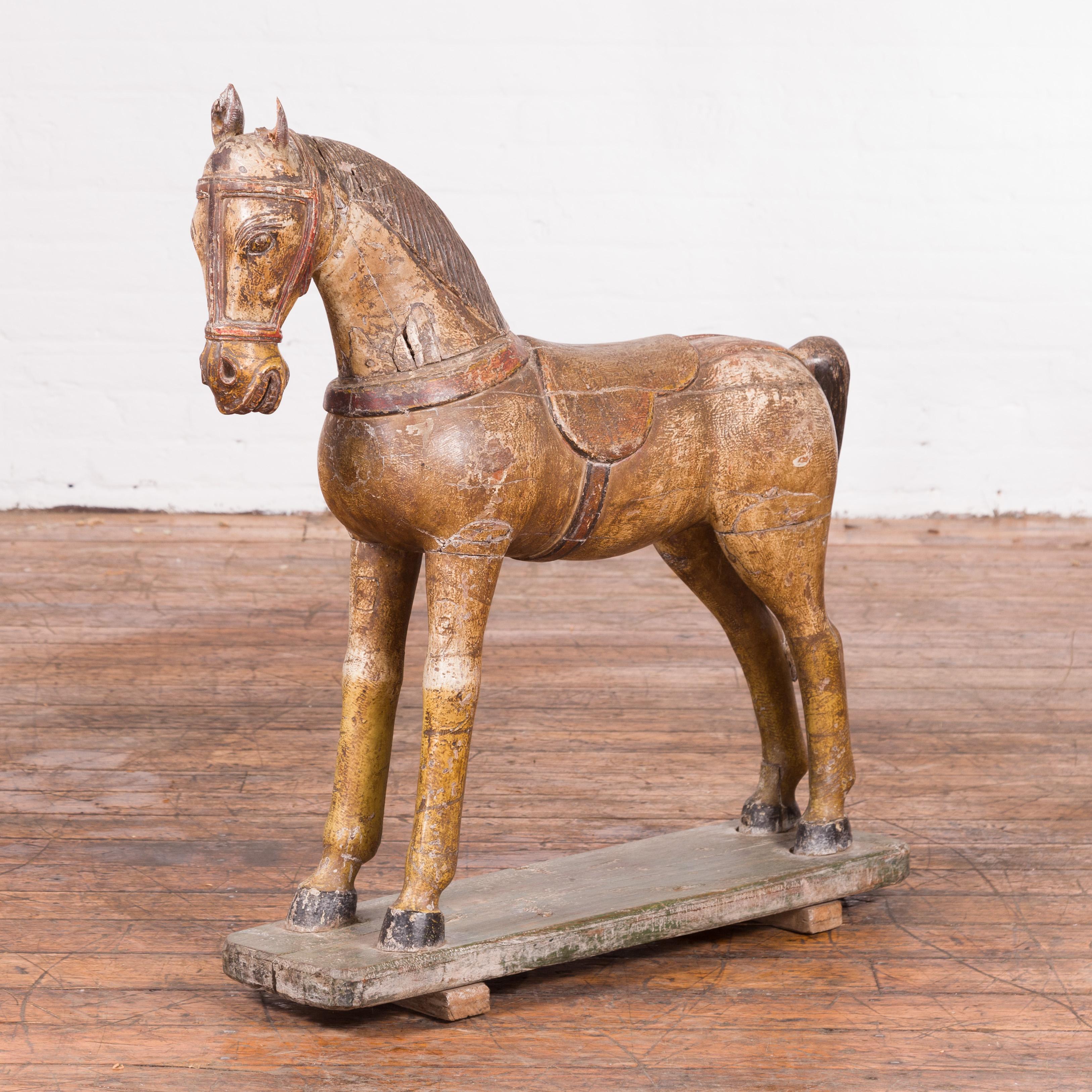 An antique Indian hand-carved multicolor wooden Mogul horse from the 20th century, with unusual color patina. Carved in India during the 20th century, this Mogul wooden horse charms us with its archaic features and distressed appearance. Standing on