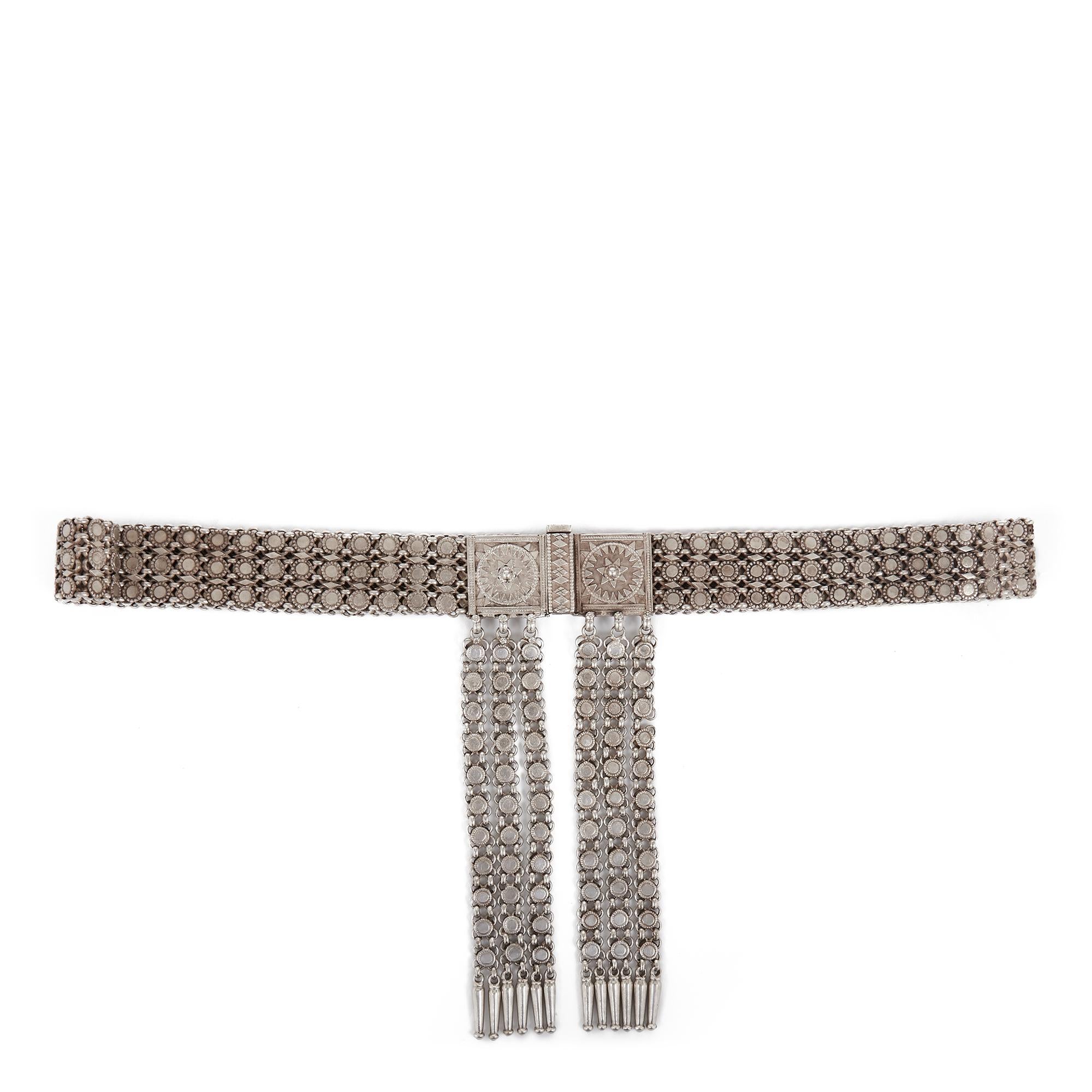 A beautiful and finely made antique Indian silver metal belt with ornate moulded square form buckle held together by a heavy twin pronged pin, the belt with a series of rounded studs set within a chainmail body and with six tassels fastened to and