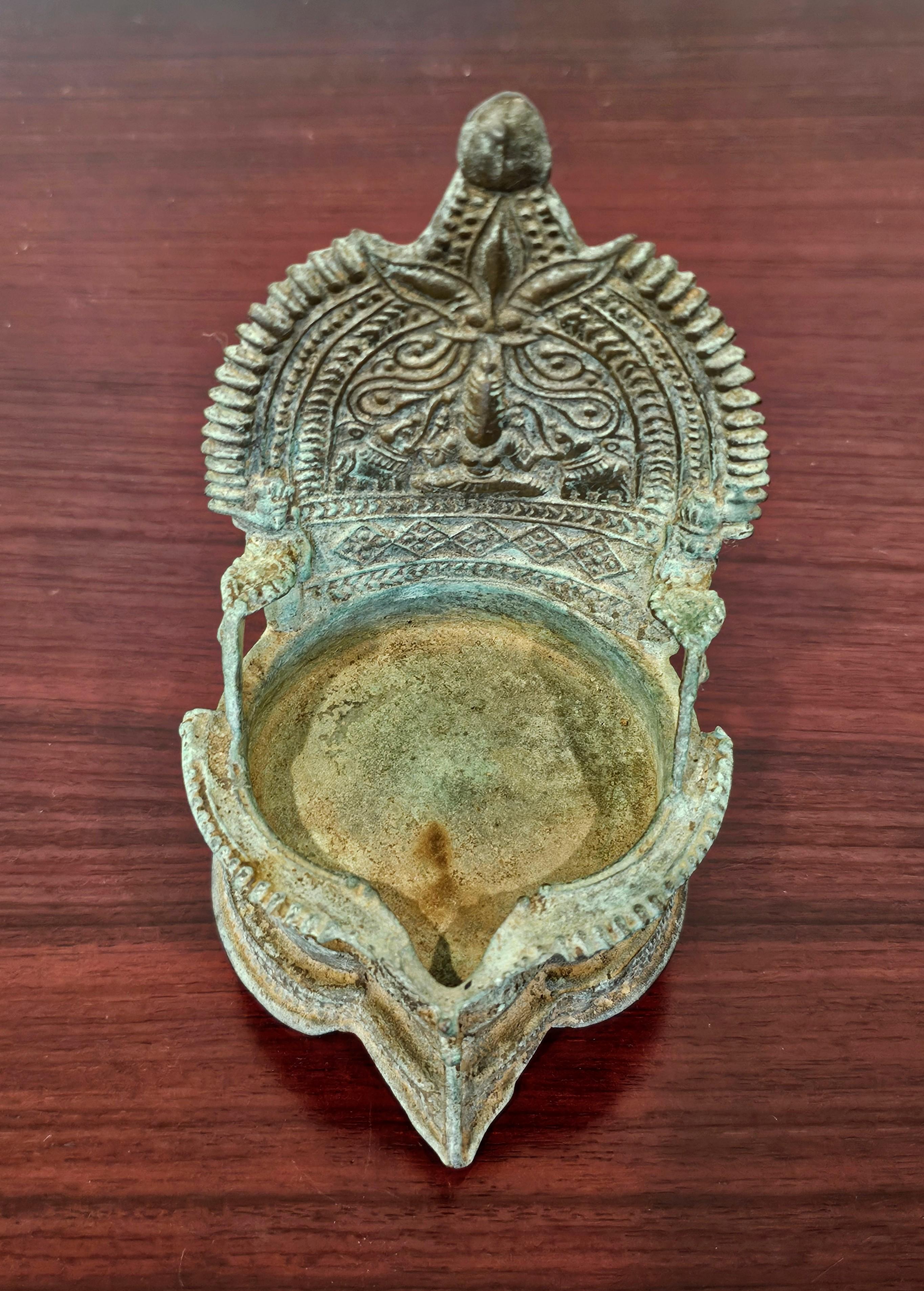 Charmante lampe à huile en métal patiné, Inde, 19e siècle ou avant. 

Probablement originaire de l'État du Tamil Nadu, dans le sud de l'Inde, richement coulée selon le célèbre procédé de bronze à la cire perdue, de forme inspirée du trône, avec une