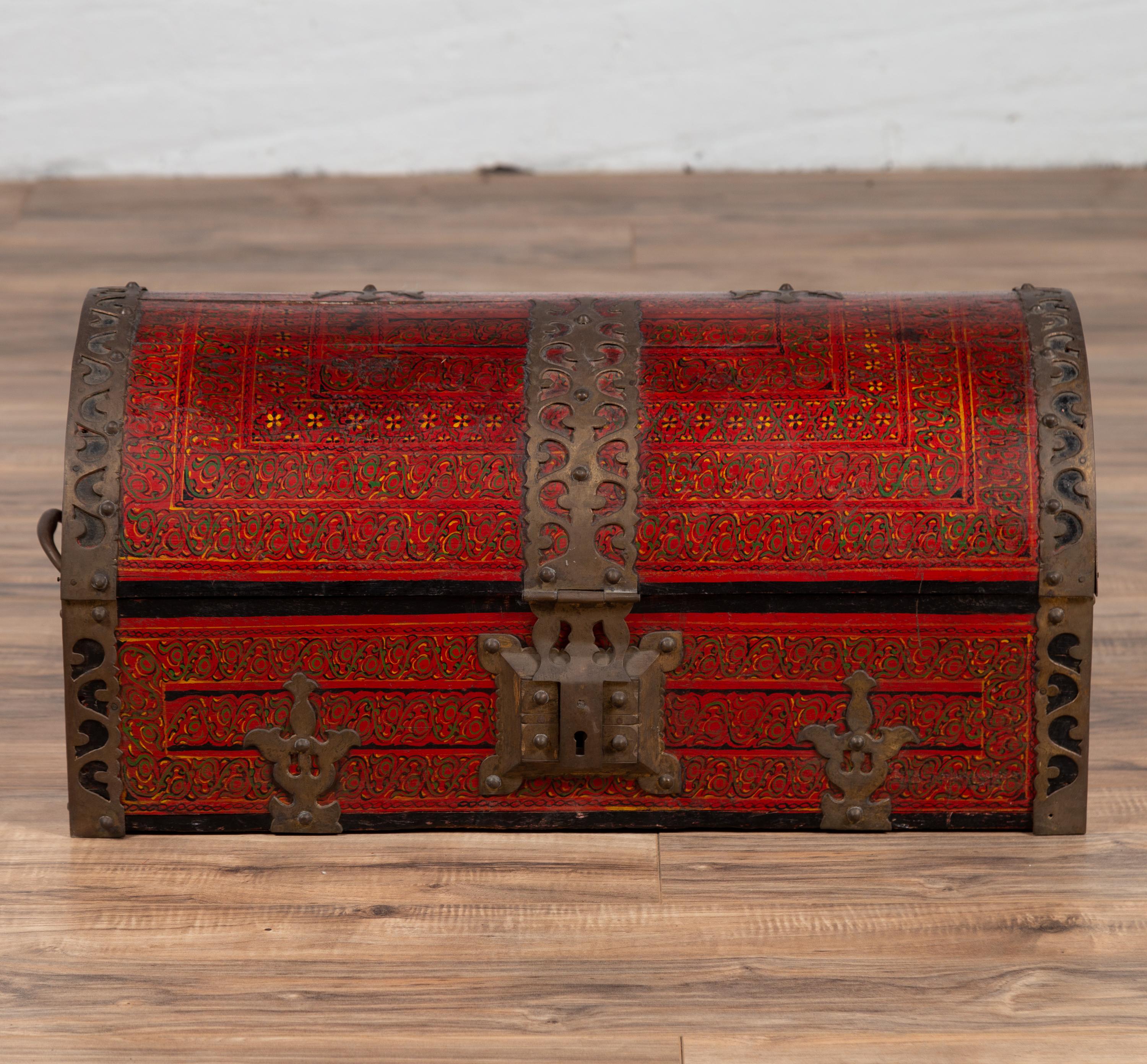 An antique Indian red lacquered dowry box from Rajasthan, with pierced brass motifs. Born in the Northern state of Rajasthan in the early years of the 20th century, this stunning dowry box features a silhouette resembling a treasure chest. Adorned