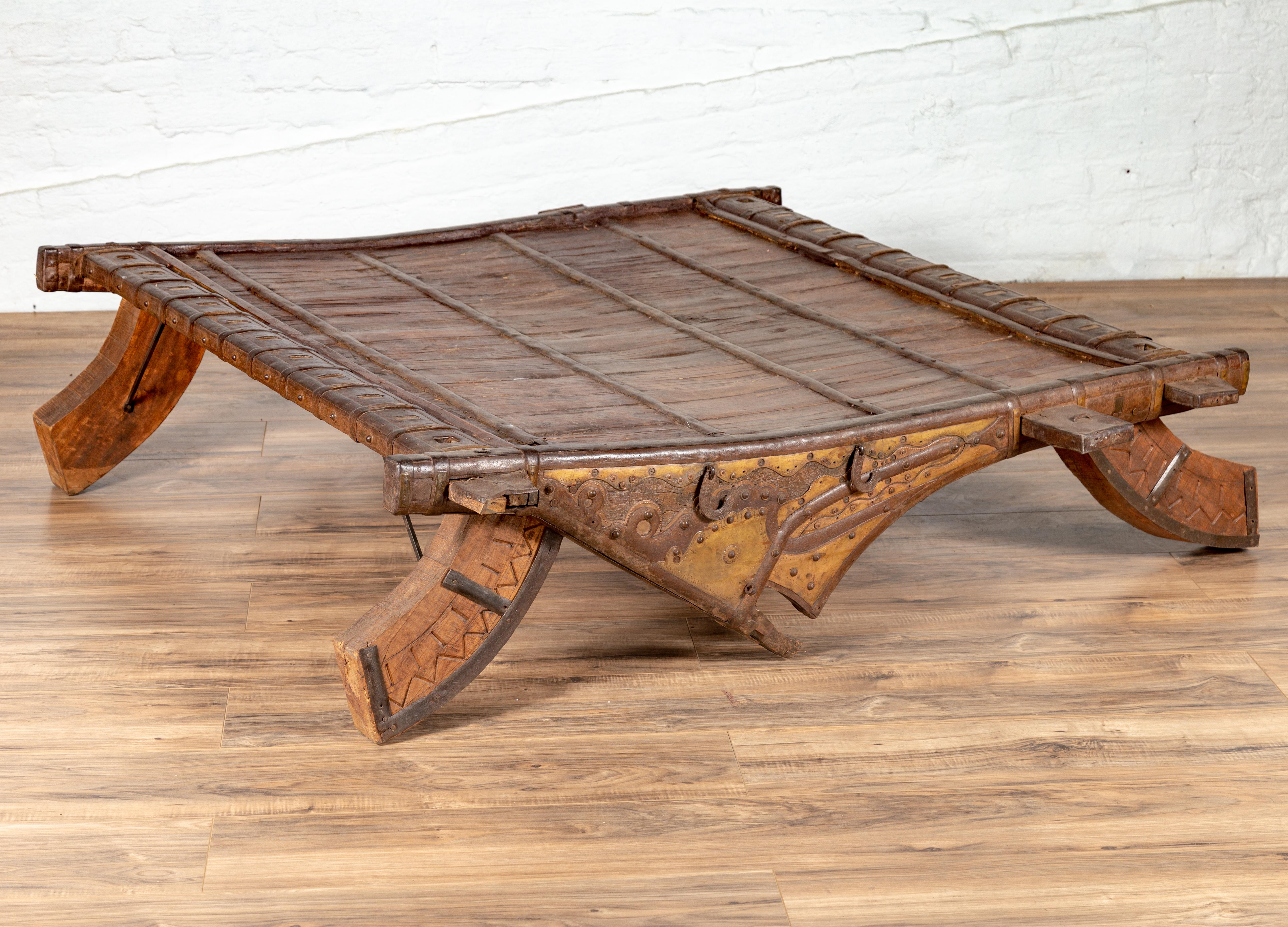 An Indian wooden ox cart with metal accents from the 19th century, made into a coffee table. We have two tables available, priced and sold individually. Perfect to be used as a coffee table, this conversation piece is an old wooden ox cart accented