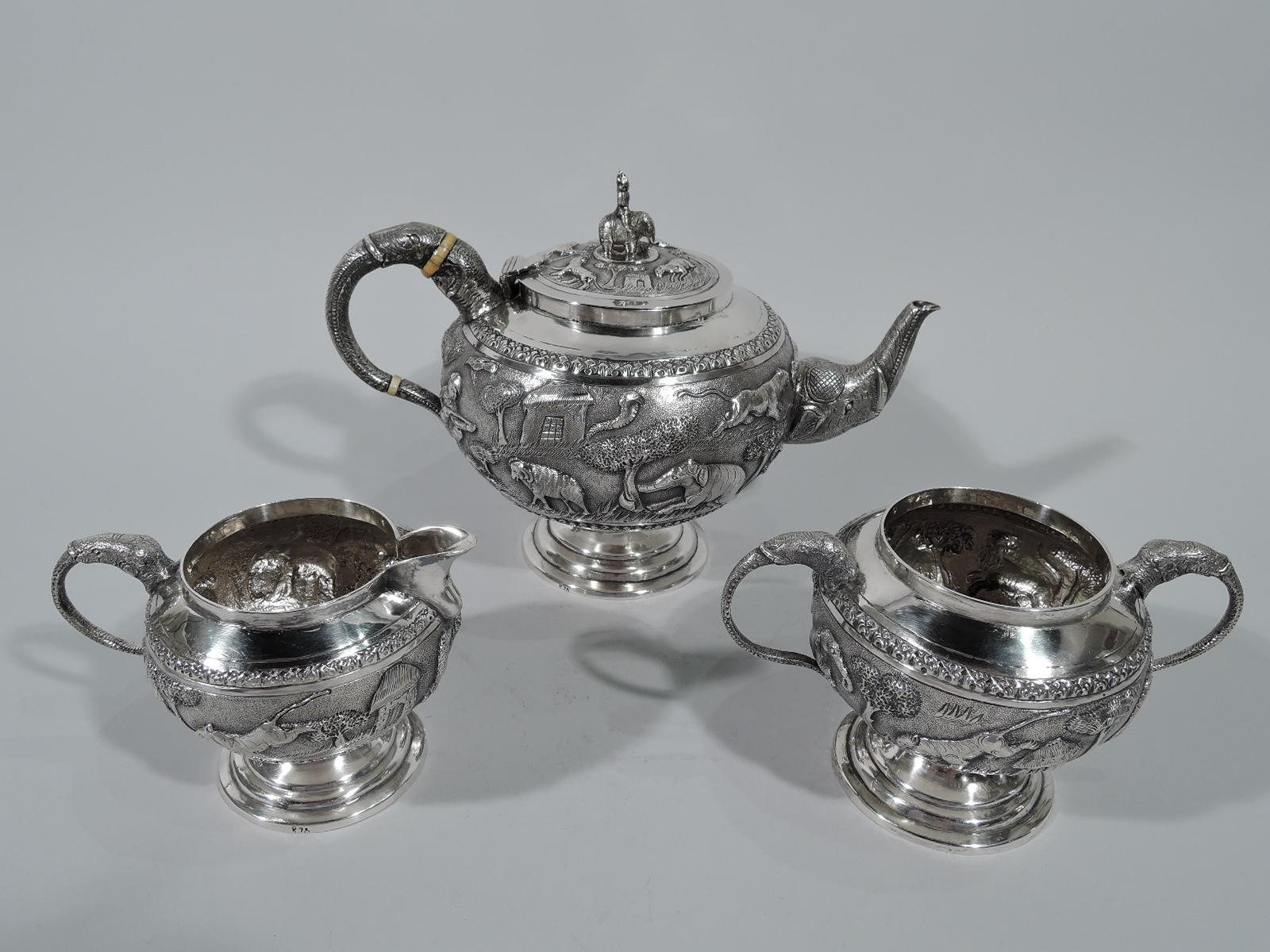 Antique Indian silver beast and man tea set. This set comprises teapot, creamer, and sugar.

Each: Globular body on stepped foot. Frieze with lions, boars, cobras, and elephants as well as native horsemen and hunters in a shadeless landscape of