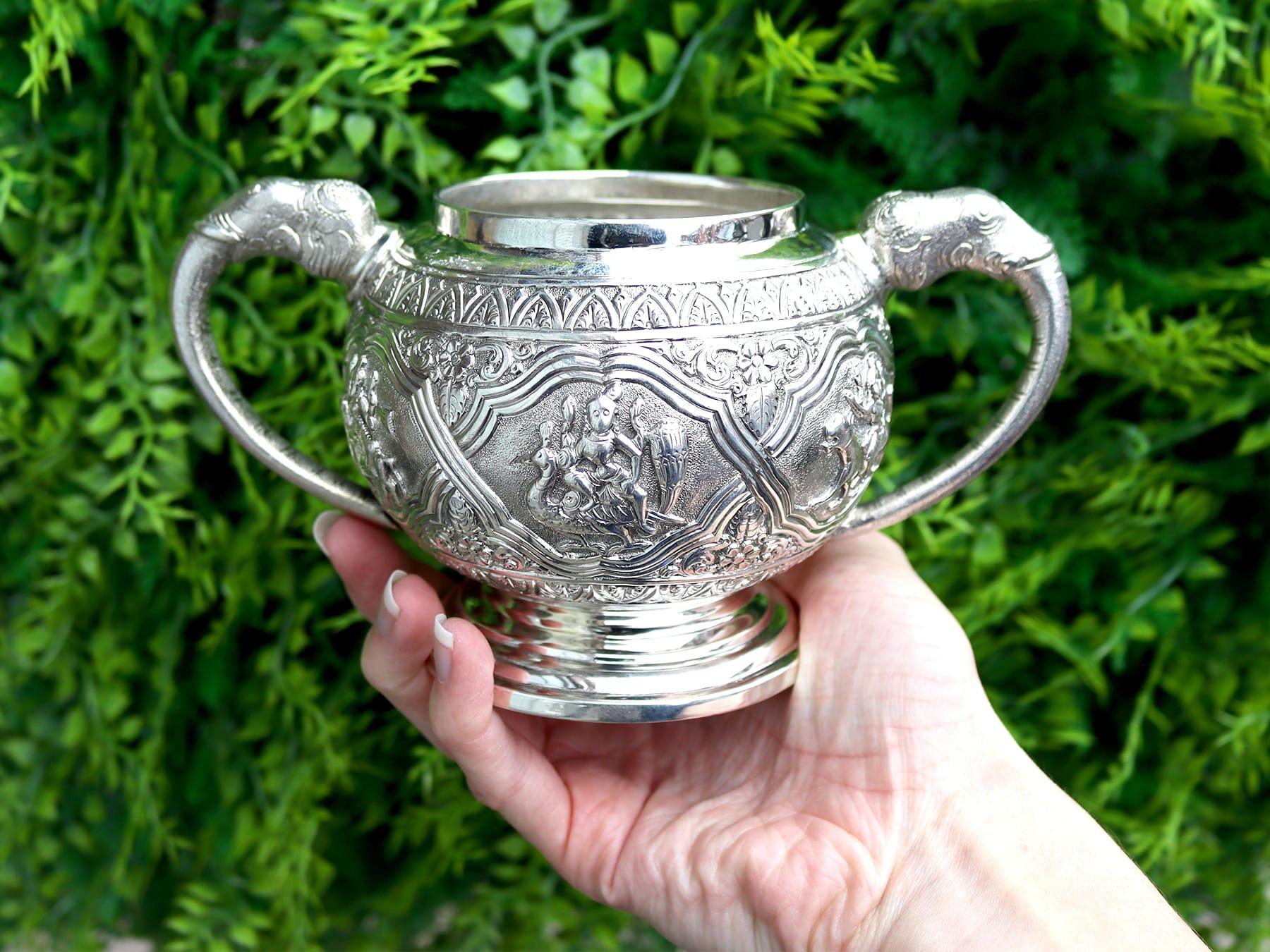 This exceptional antique Indian sterling silver sugar bowl has a circular form onto a spreading foot.

The body of this exceptional silver bowl is embellished with impressive chased leaf decoration, accented with a central broad interlacing band