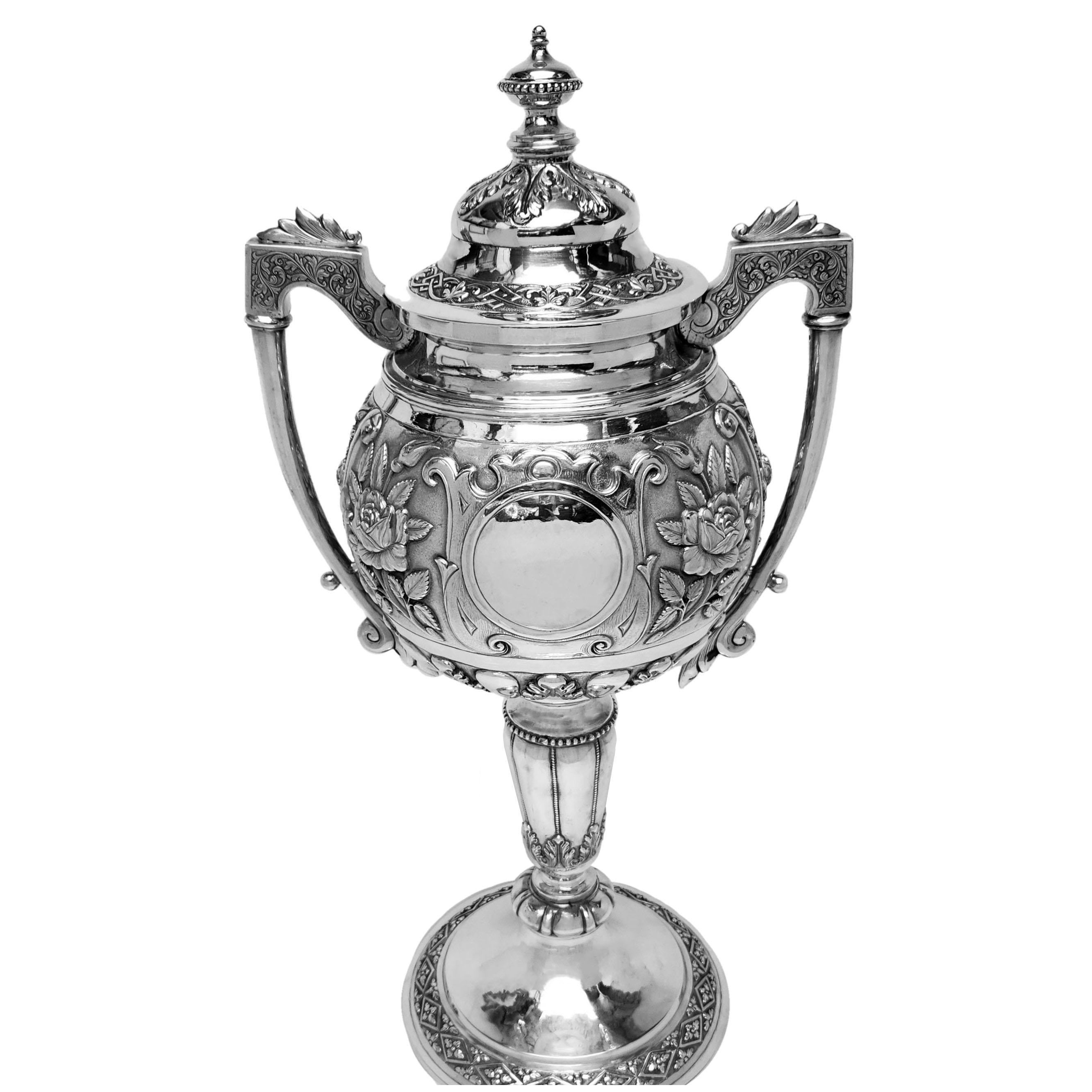A magnificent Antique Indian Two Handled Cup & Cover with an unusual spherical form on top of  tall column. The body of the Cup is embellished with beautiful chased floral patterns surrounding a pair of round cartouches. The Lid, Foot and Column are