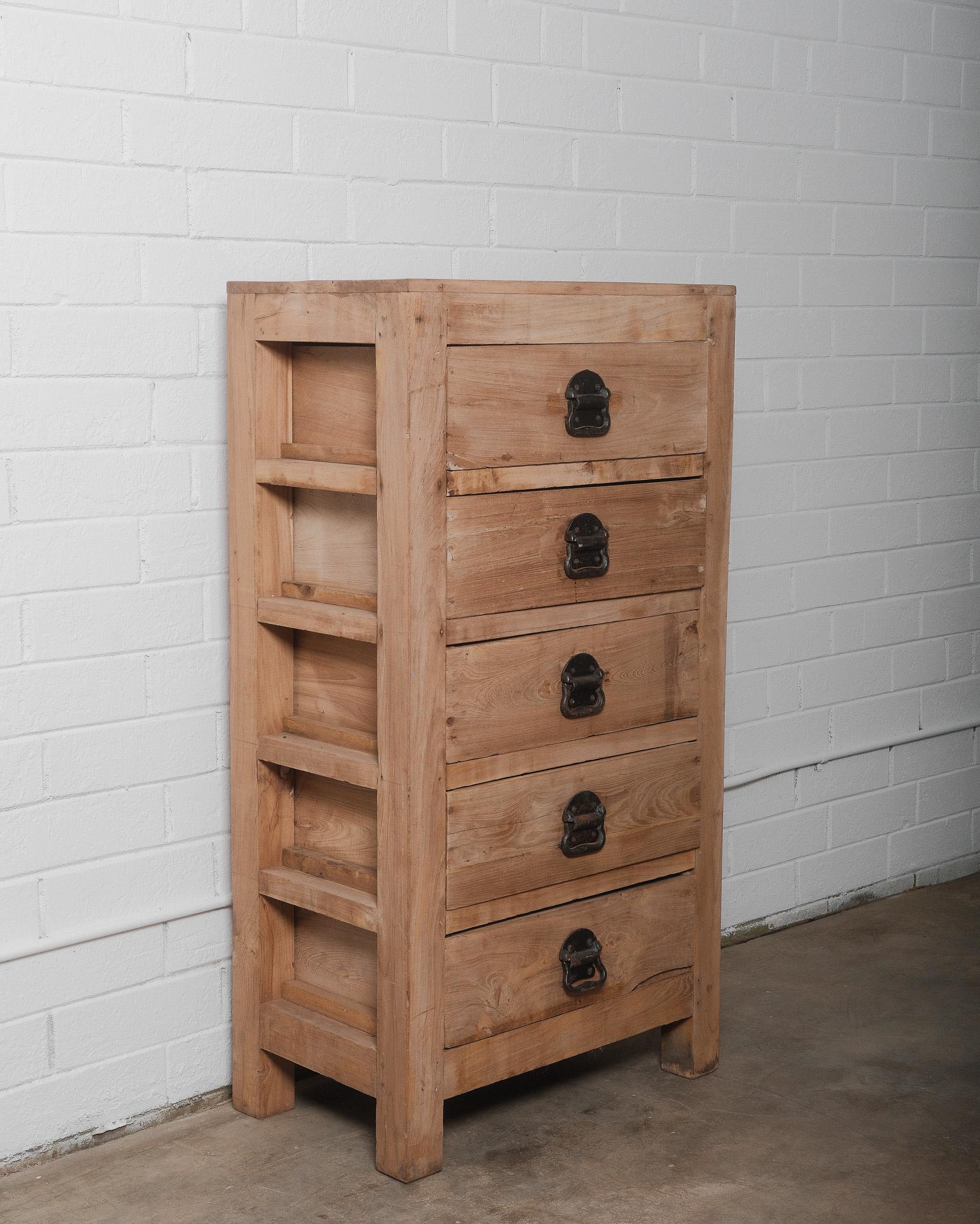 Questa antica cassettiera indiana, realizzata in legno massiccio, è un esempio intramontabile di artigianato tradizionale indiano. Caratterizzato da una patina naturale di legno grezzo che ne evidenzia le venature organiche e il carattere, questo