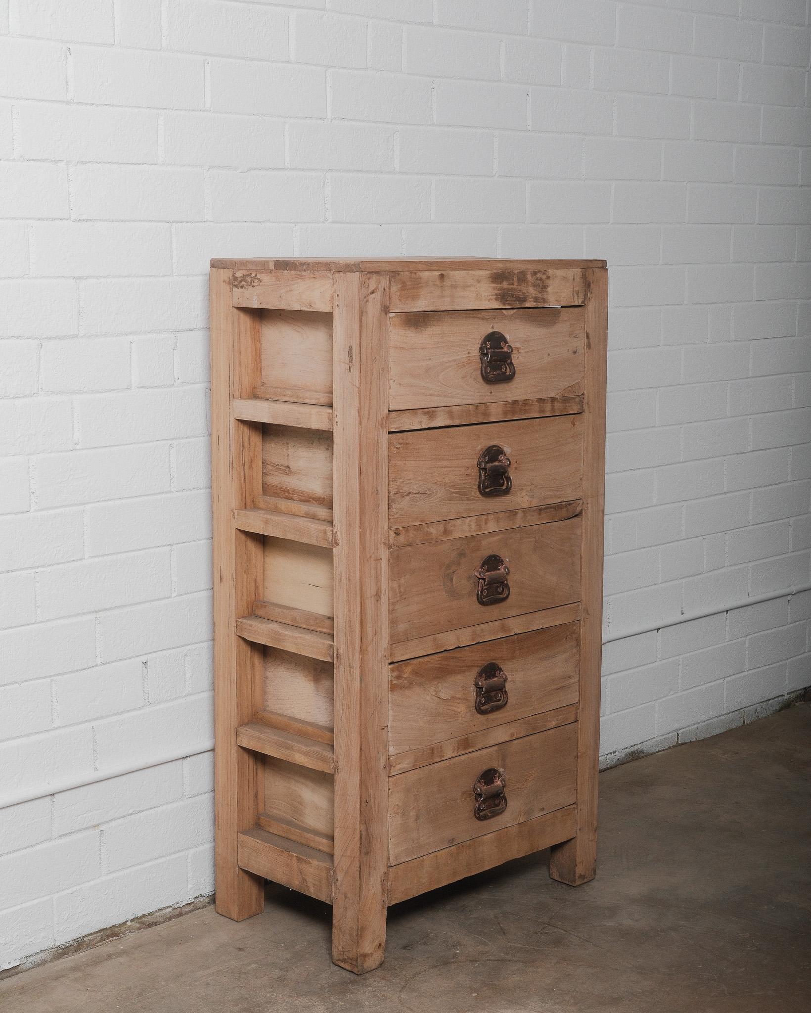 Questa antica cassettiera indiana, realizzata in legno massiccio, è un esempio intramontabile di artigianato tradizionale indiano. Caratterizzato da una patina naturale di legno grezzo che ne evidenzia le venature organiche e il carattere, questo