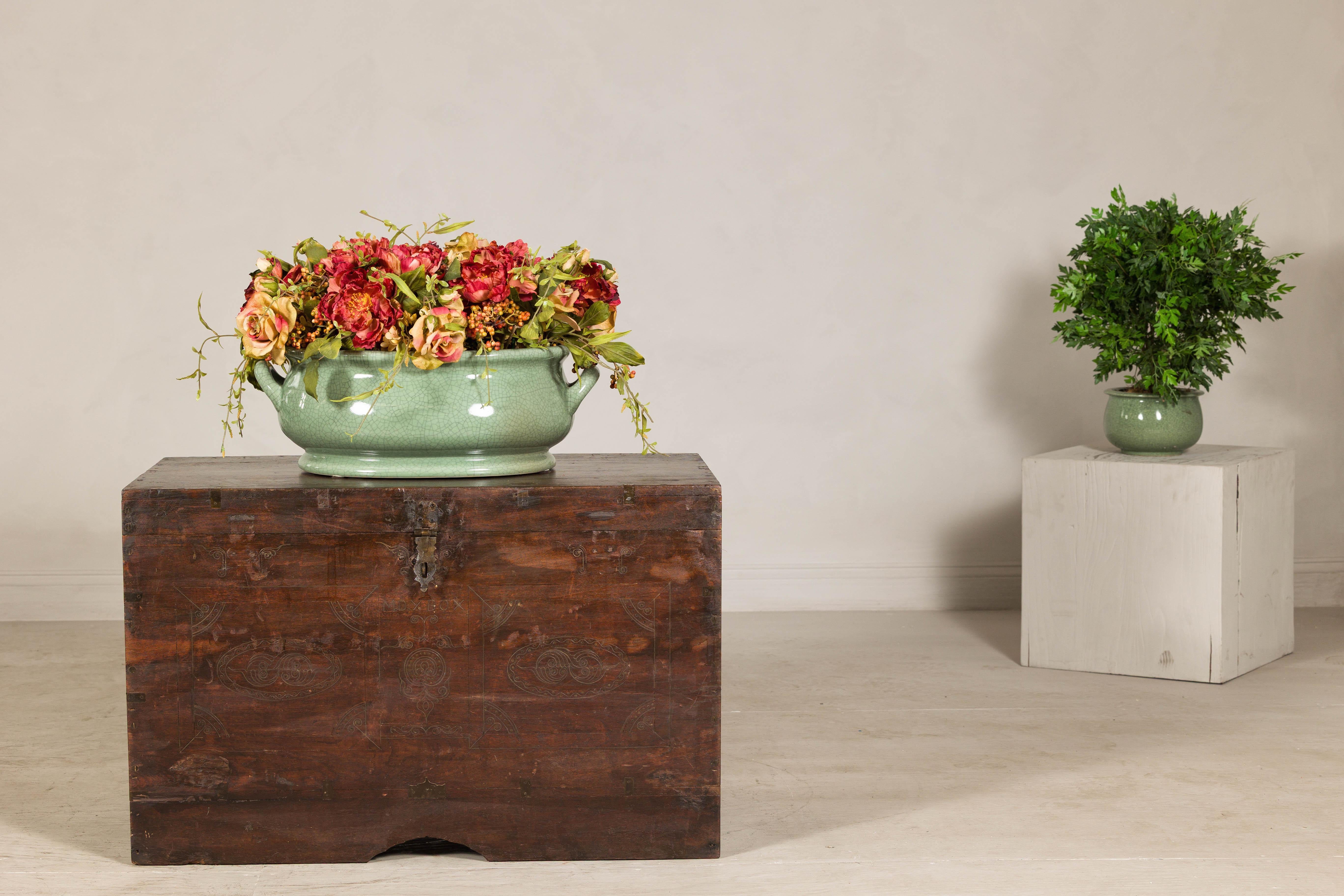 This antique Indian wedding trunk is a striking blend of function and artistry, designed to store treasured heirlooms with a touch of grandeur. Crafted from solid wood, likely teak or sheesham, it showcases a discreet incised carved décor on the