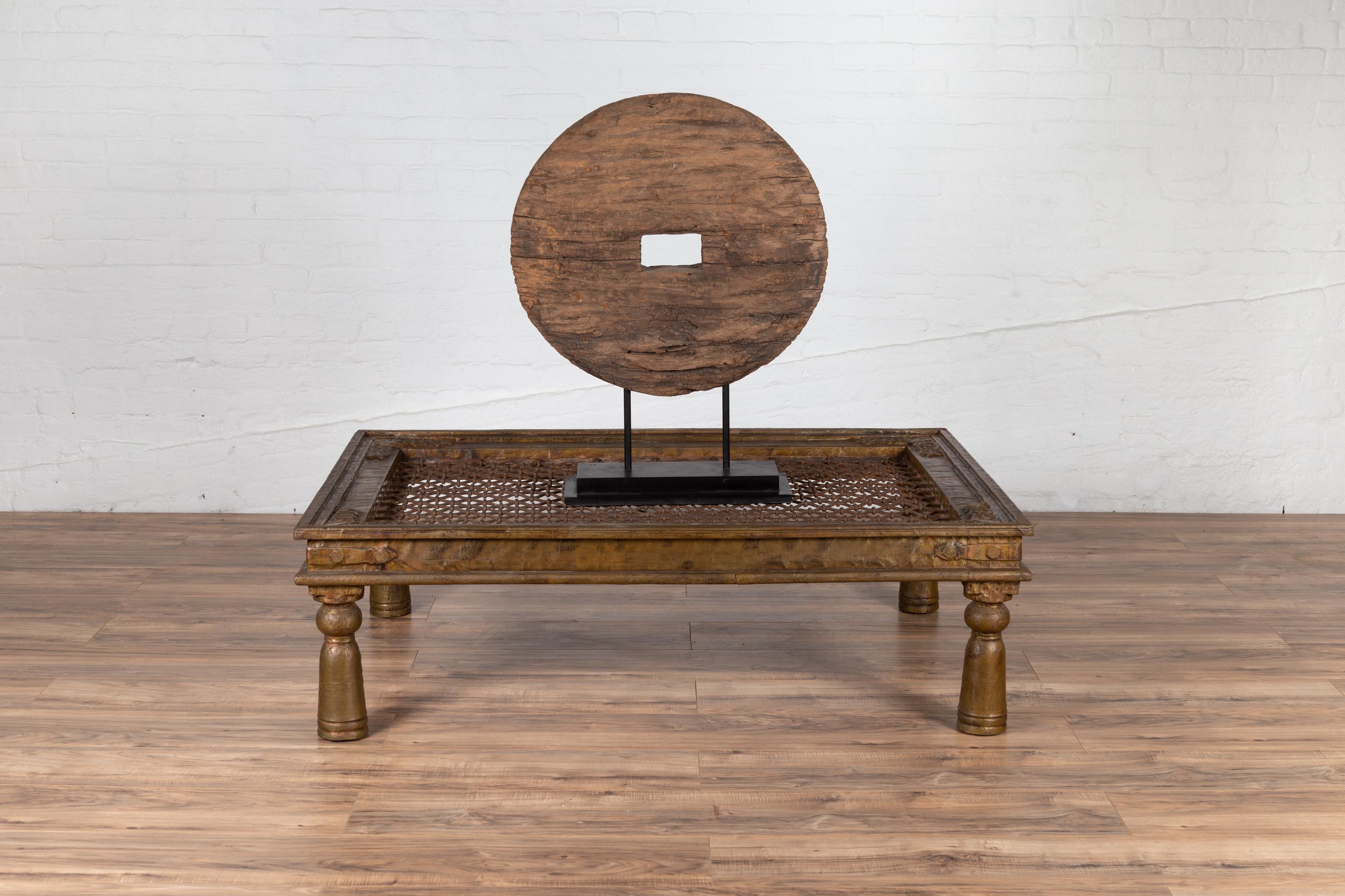 An Indian open iron design coffee table made of an antique window grate inset into a wooden structure accented with copper sheathing. Born in India during the early years of the 20th century, this Indian window grate is resting on four turned