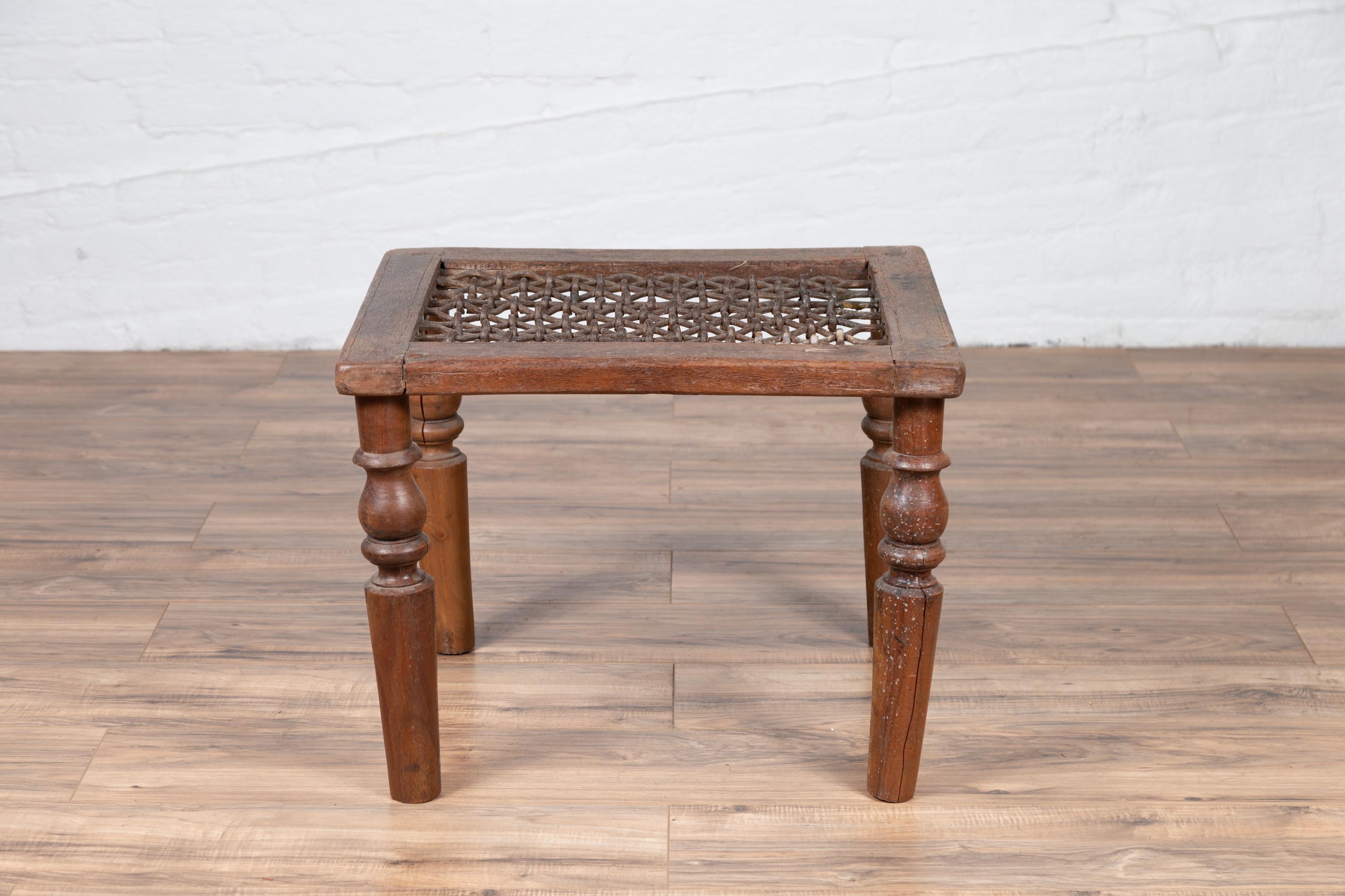 Une ancienne grille de fenêtre indienne du 19e siècle, transformée en table basse. Née en Inde au XIXe siècle, cette table indienne présente un plateau en fer à motifs géométriques, reposant sur quatre pieds tournés de type balustre qui présentent