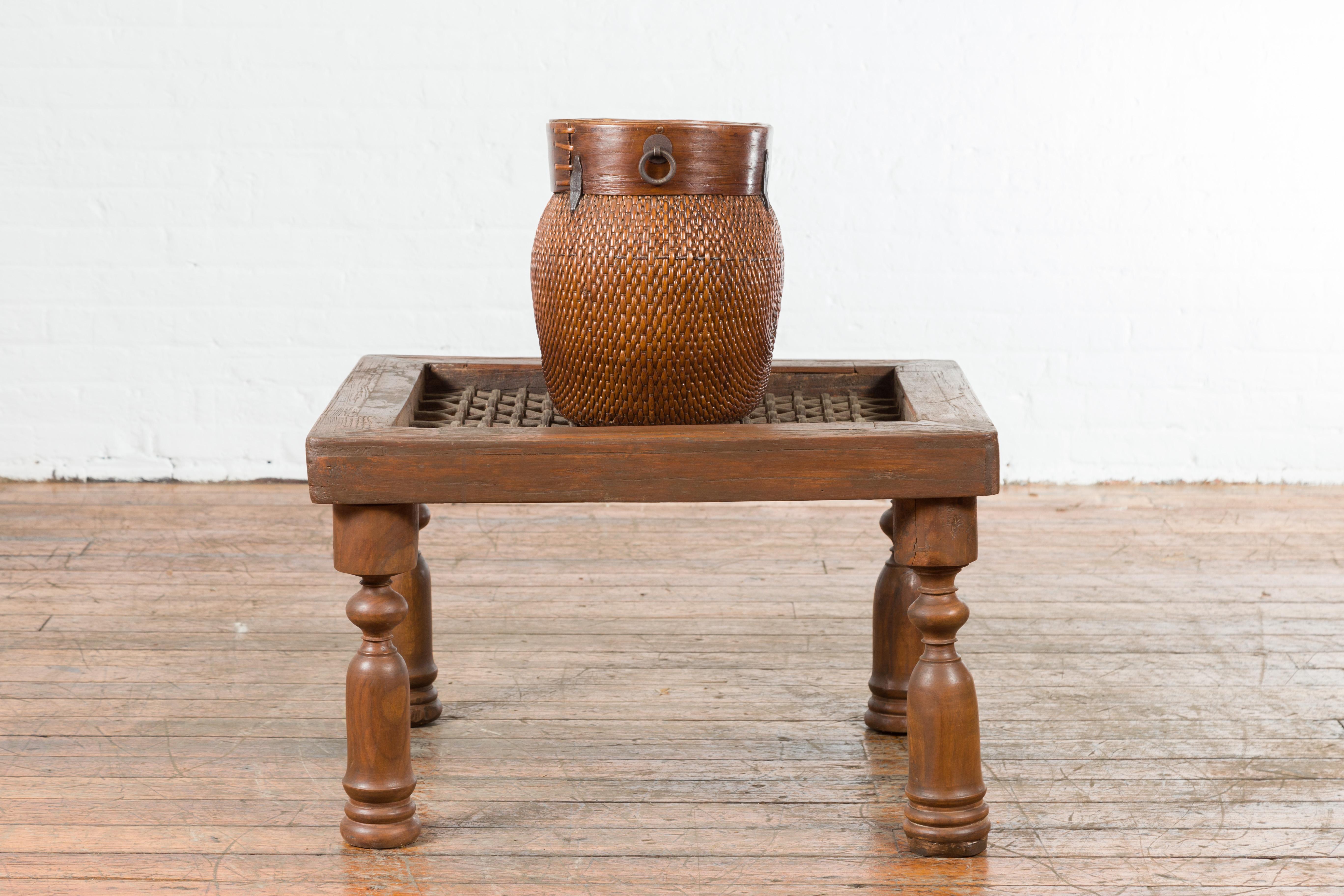 An antique Indian window grate from the early 20th century, made into a square-shaped coffee table. Created in India during the early years of the 20th century, this coffee table features an iron grate top with geometric patterns, resting on four