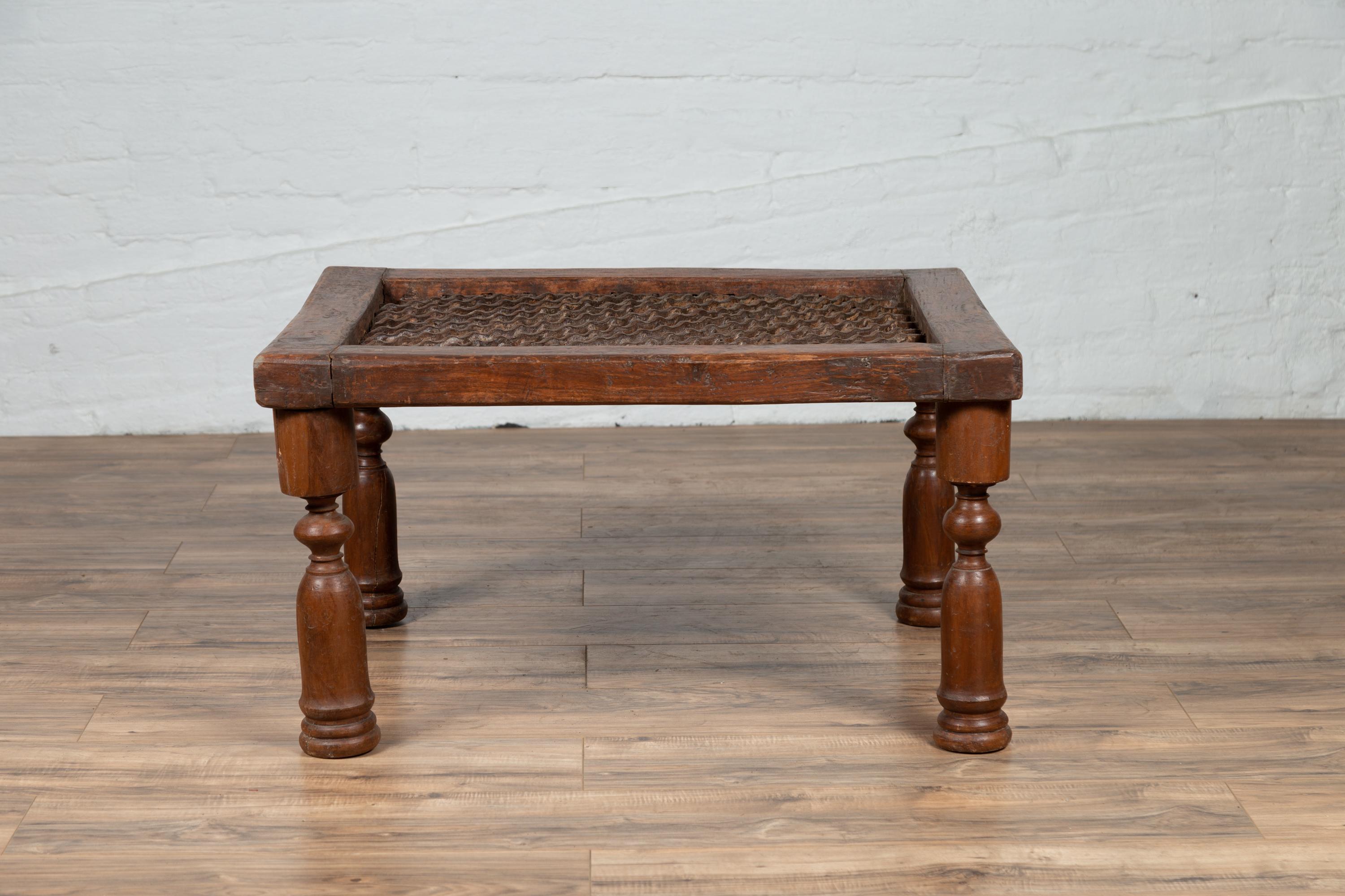 An antique Indian window grate from the early 20th century, made into a low side table. Born in India during the early years of the 20th century, this Indian window grate is resting on four turned baluster-type legs. Perfectly rustic and boasting a