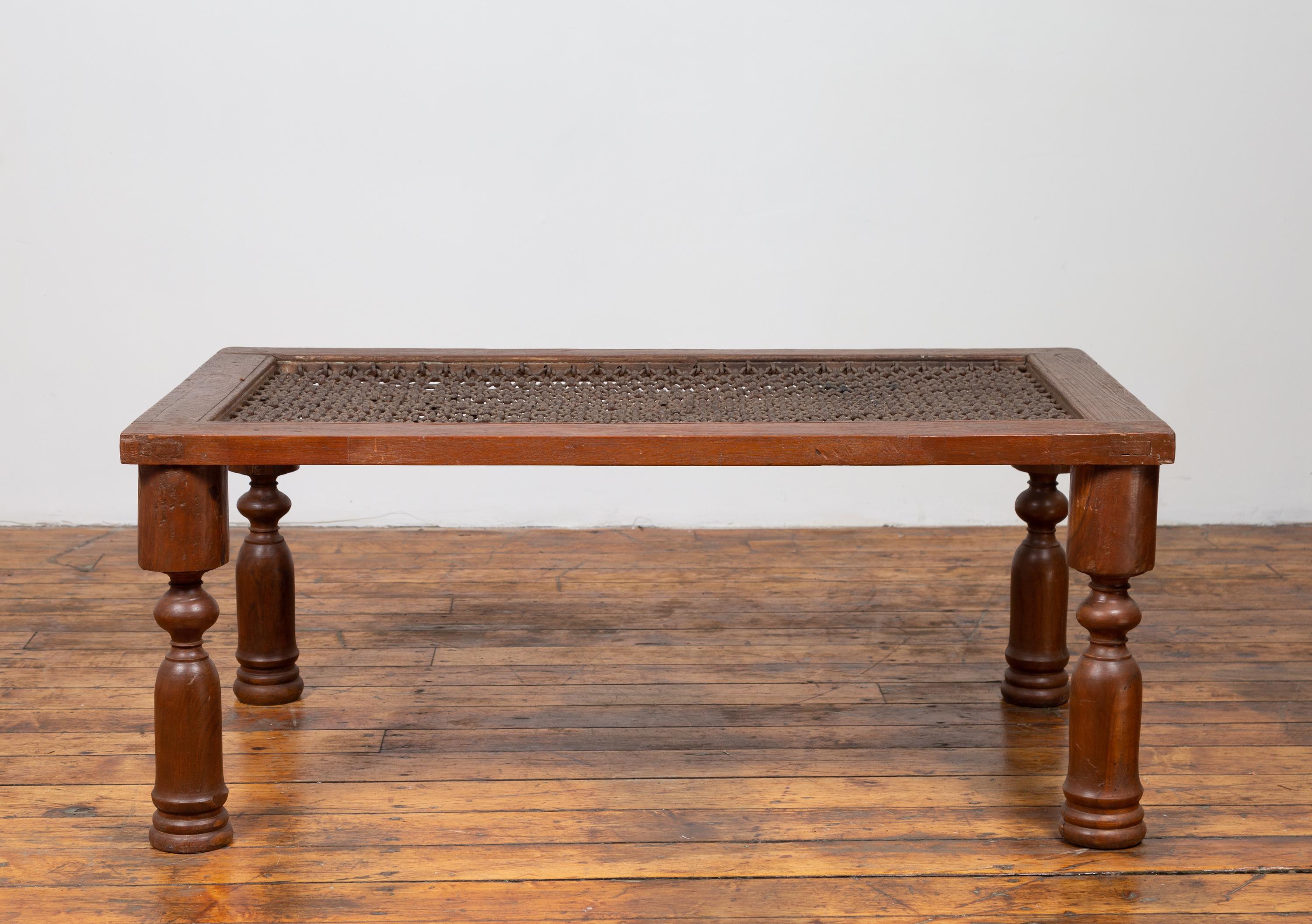 An antique Indian coffee table from the early 20th century, with window grate and turned legs. Born in India during the early years of the 20th century, this Indian coffee table features a rectangular top made of a window grate, resting on four