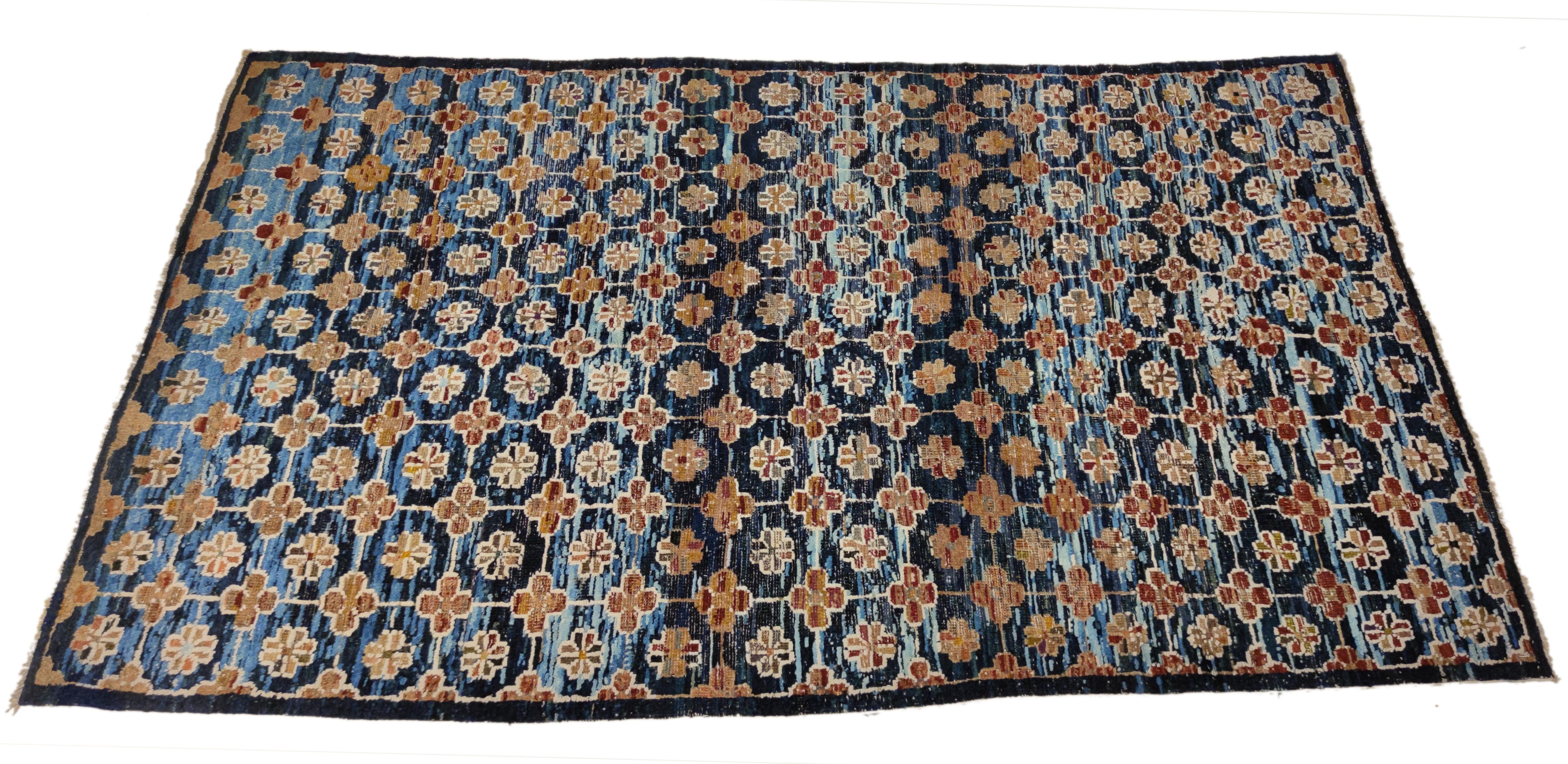 Rare et inhabituel tapis chinois décoré d'un motif de rosettes à huit pétales, reliées entre elles pour former un treillis dans le négatif duquel se trouve le motif de la longévité, qui est l'un des principaux éléments décoratifs que l'on trouve sur