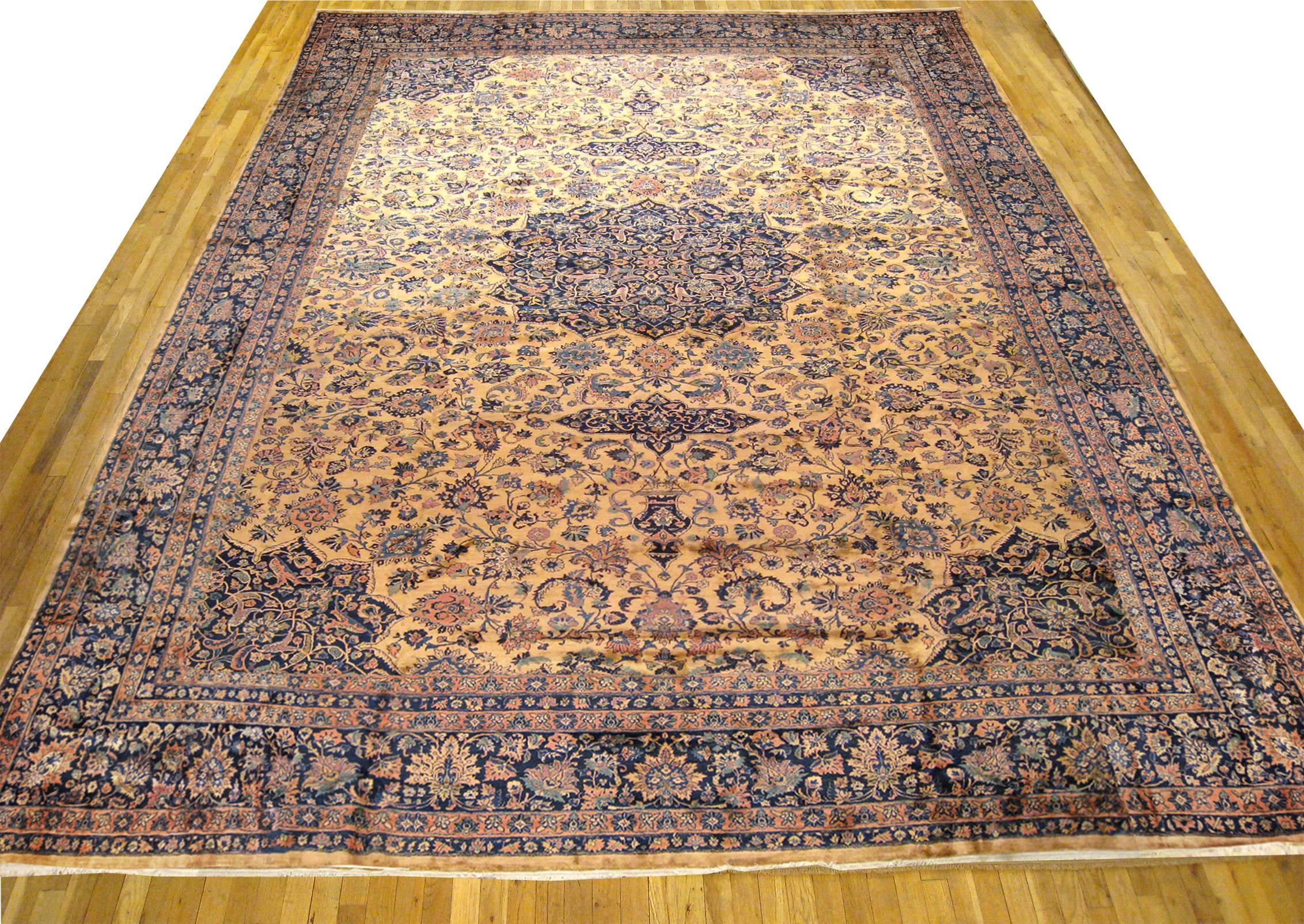 An antique Indo-Kashan oriental carpet, size 22'4 H x 16'0 W, circa 1920. This massive hand-knotted wool carpet features a fine 'Tufjanchian' style weave, and is characterized by a blue central medallion with corresponding corner spandrels, but with