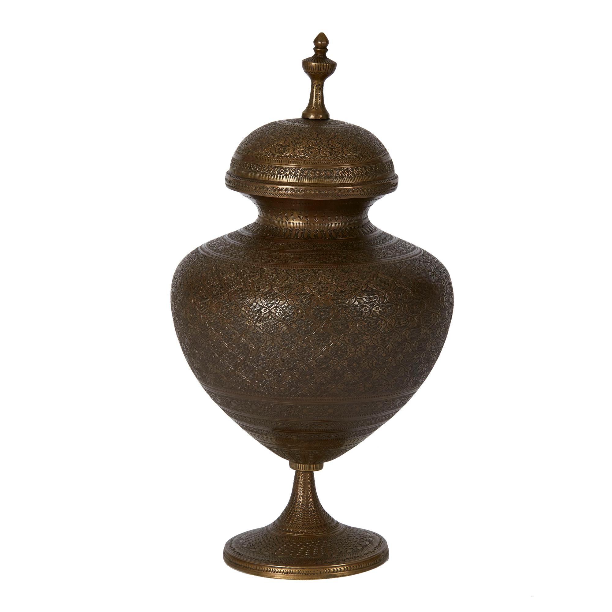 An impressive antique Indo-Persian bronze lidded pedestal vase, the bulbous body extensively decorated with finely engraved patterning and fitted with a domed cover with raised finial and supported on a narrow pedestal base on a rounded and slightly