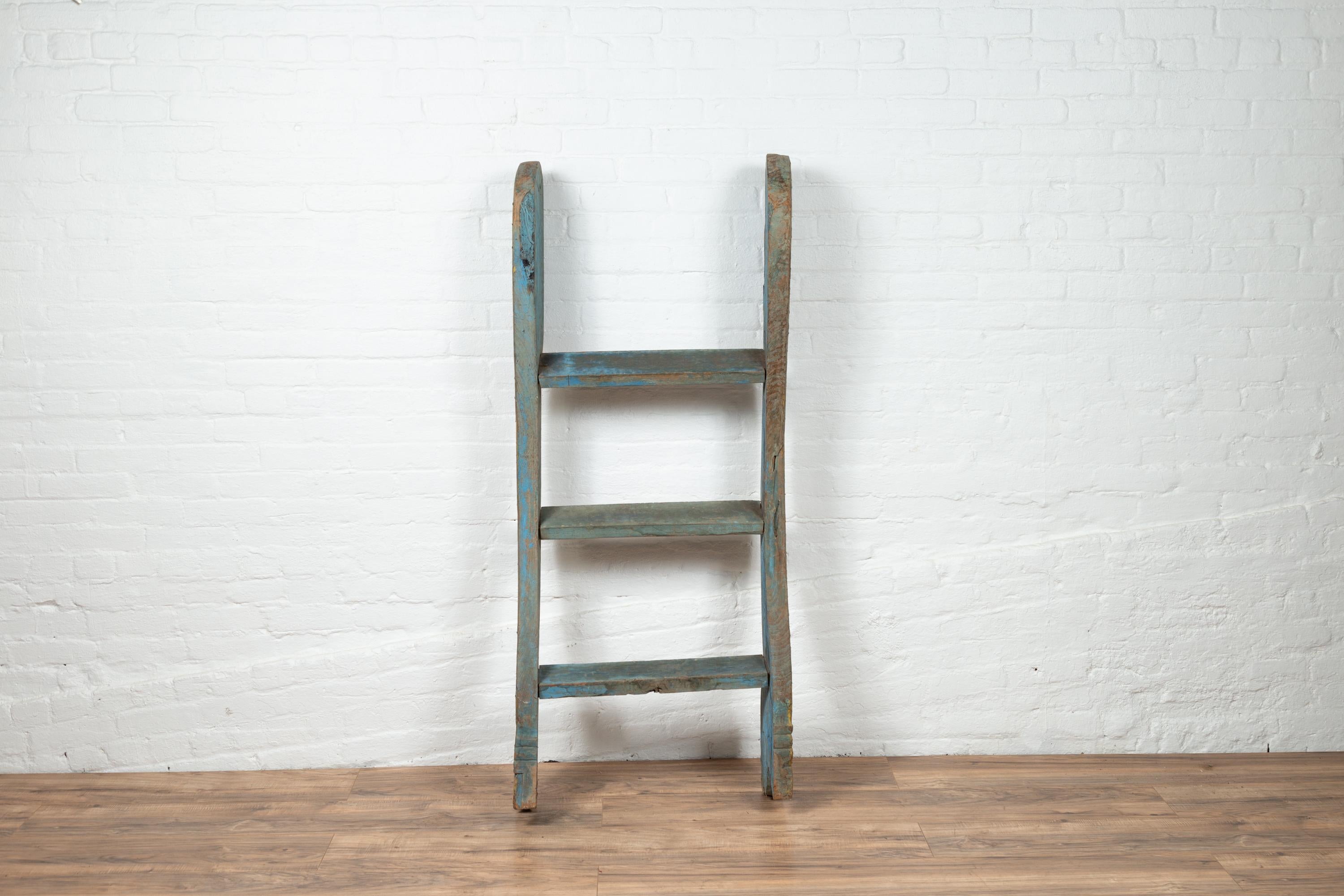 An antique Indonesian blue carved ladder from the early 20th century, with painted and gilt accents. Born in Indonesia during the early years of the 20th century, this charming painted ladder will be a wonderful decorative accent in any room.
