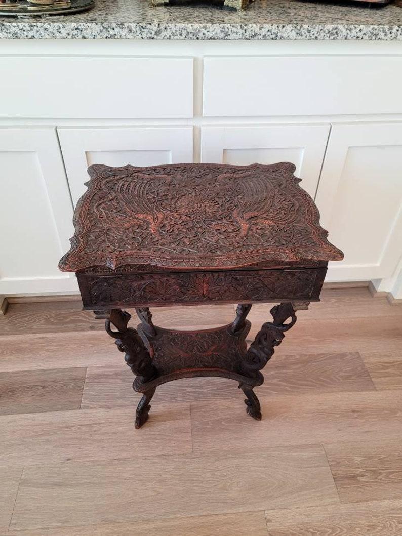 A profusely carved antique Southeast Asian sewing work table with beautifully aged patina of warm and rich coloring. 

Exquisitely handcrafted in Indonesia in the late 19th century, exceptionally executed, featuring an ornate cartouche shaped