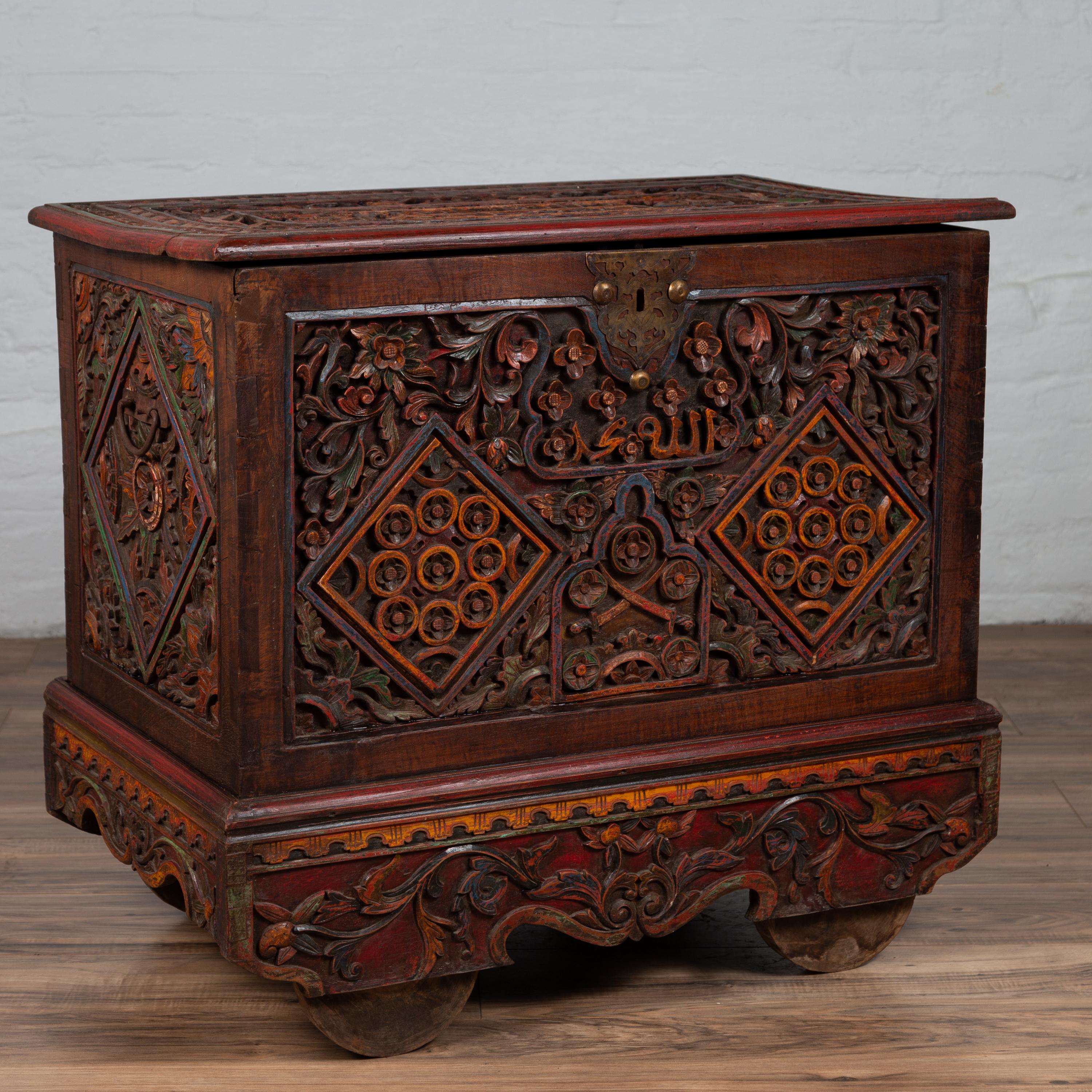 An antique Indonesian hand carved blanket chest from the early 20th century, with intricate floral motifs, underglaze patina and wheels. Born in Indonesia during the early years of the 20th century, this exquisite blanket chest captures our