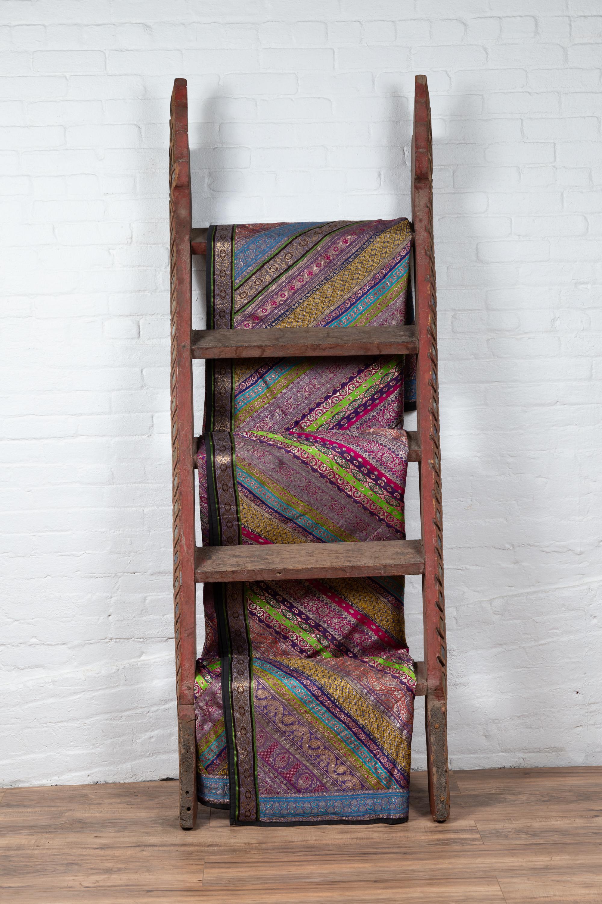 An Indonesian pink / light red hand carved ladder from the early 20th century with flaming shape and colorful glass inlay. Born in Indonesia during the early years of the 20th century, this charming painted ladder will be a wonderful decorative